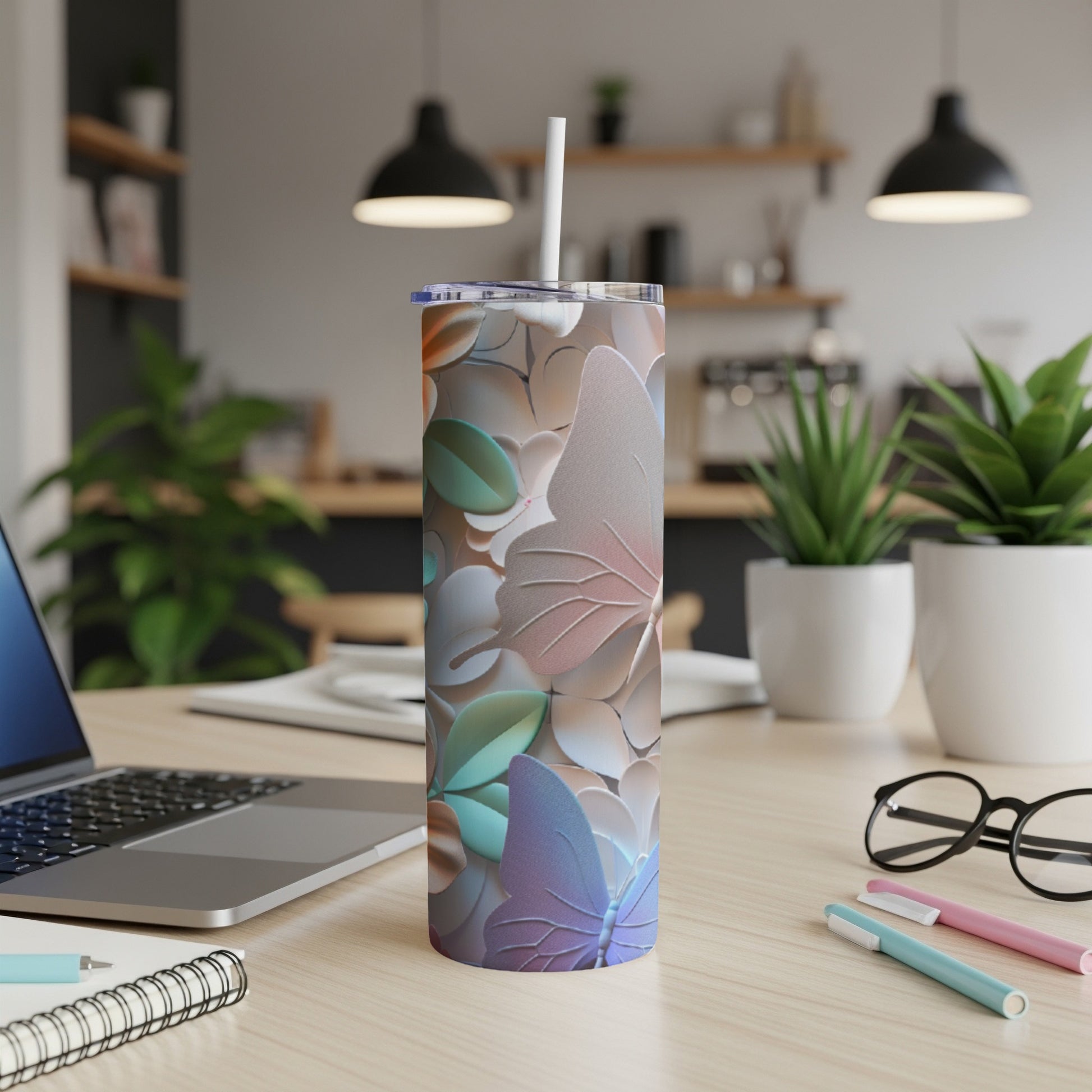 Tall tumbler with butterfly and floral design on a desk.