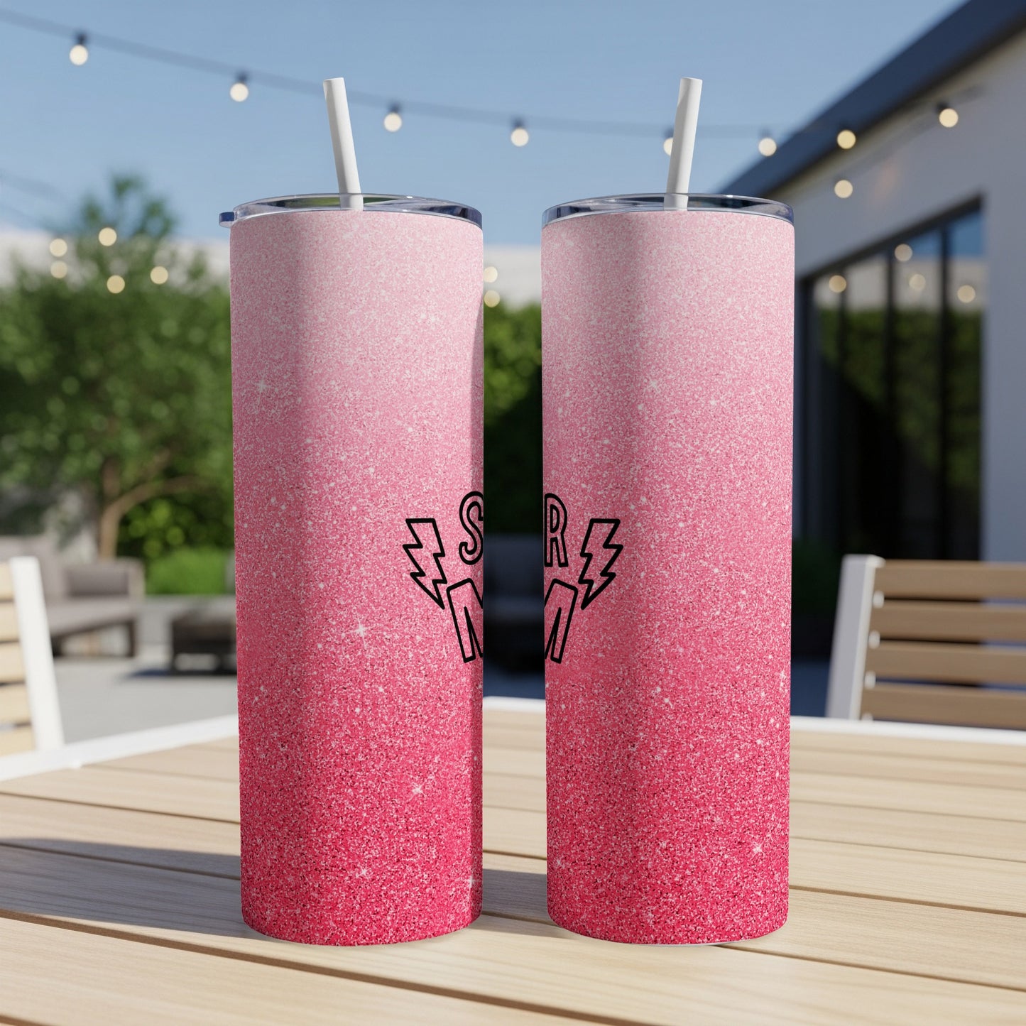 Pink glitter tumbler with "Super Mom" text, on a wooden table outdoors.