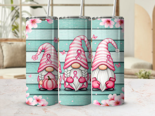 Three gnomes in pink striped hats with ribbon accents on a wooden background with flowers.