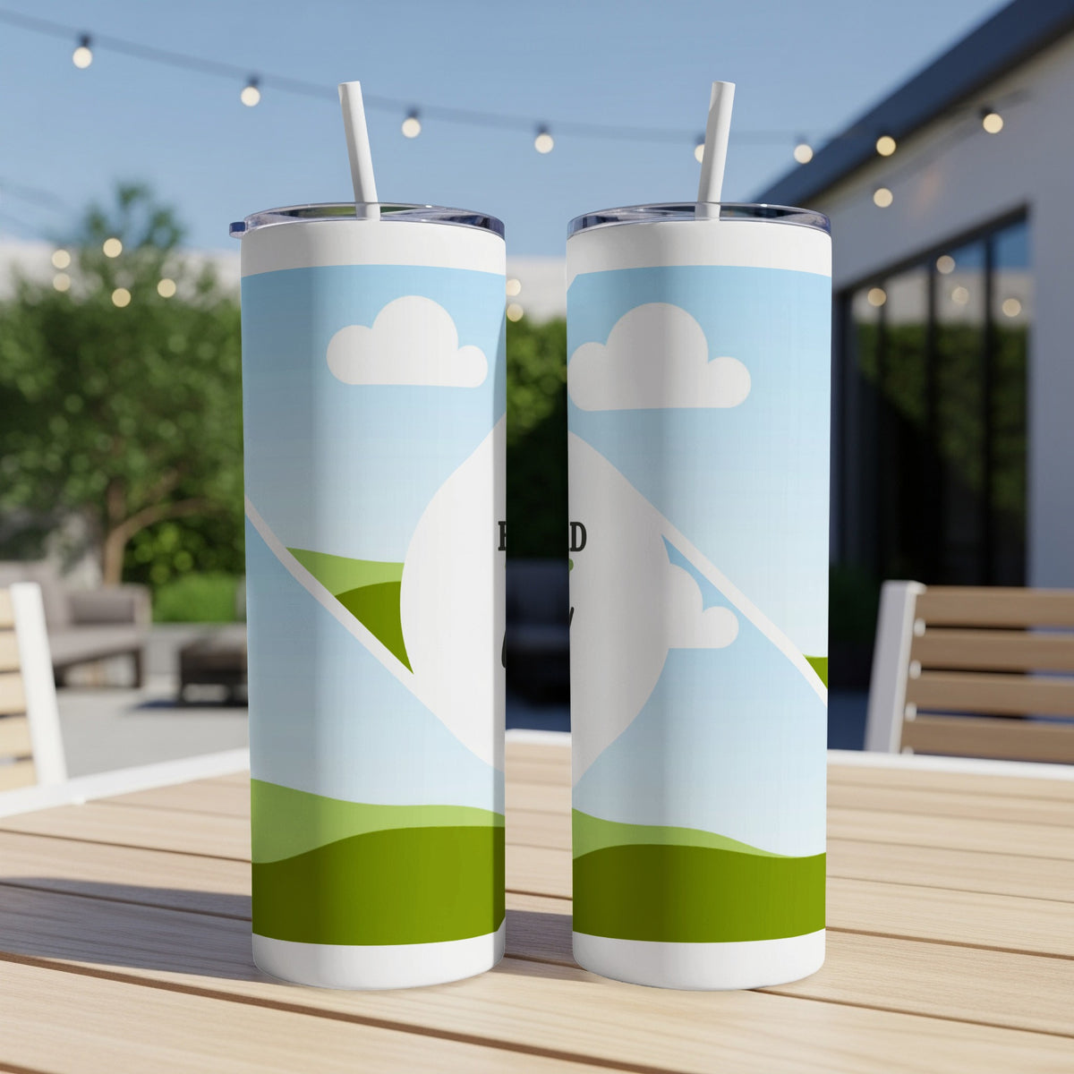 Two tumblers with sky and rolling green hills design, on a wooden table.