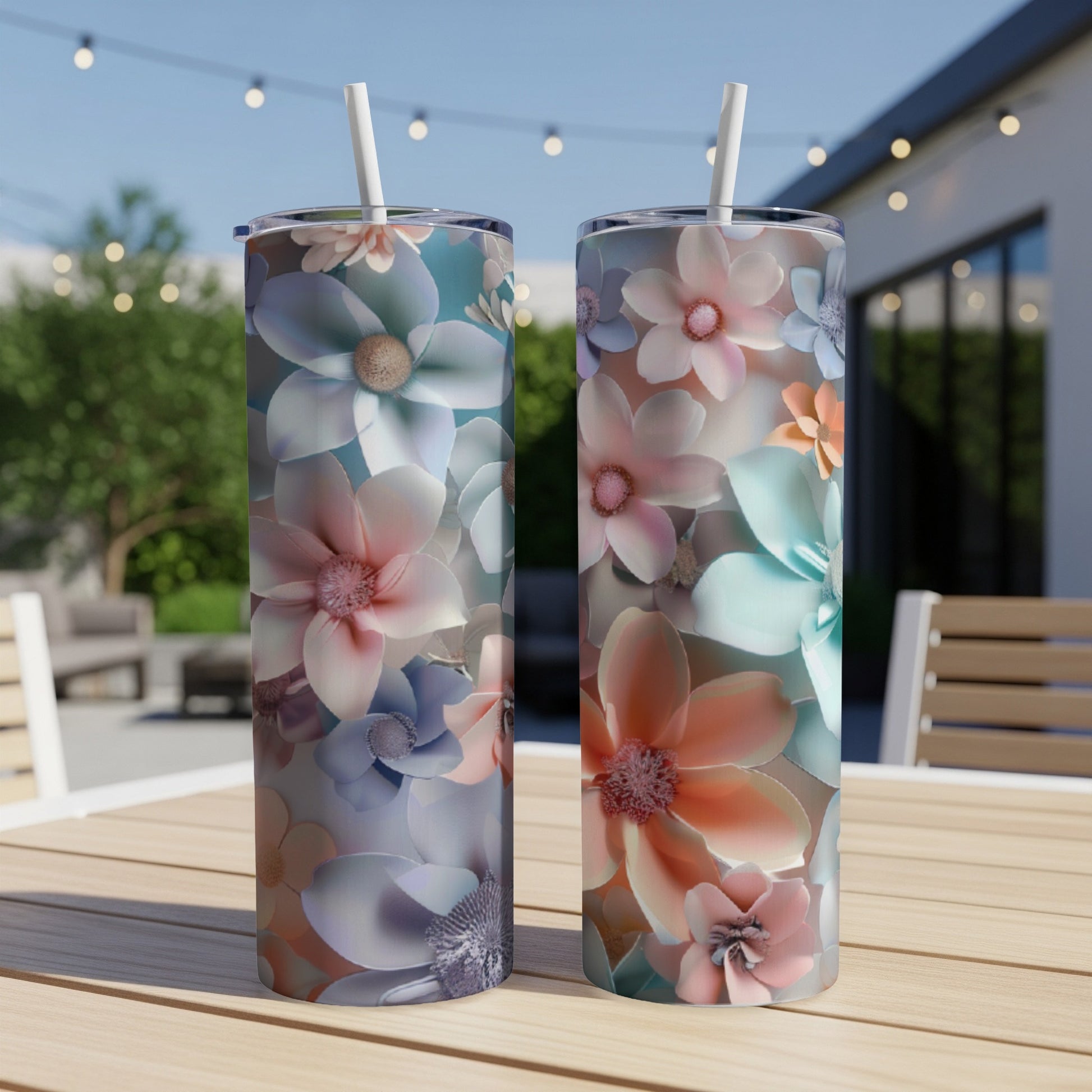 Two tumblers with a floral pattern sit on a wooden table outdoors.
