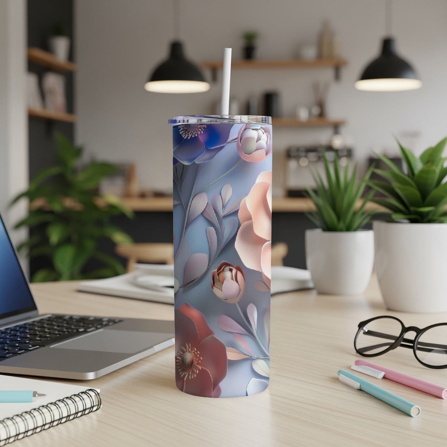 Floral pattern tumbler with straw on a desk.