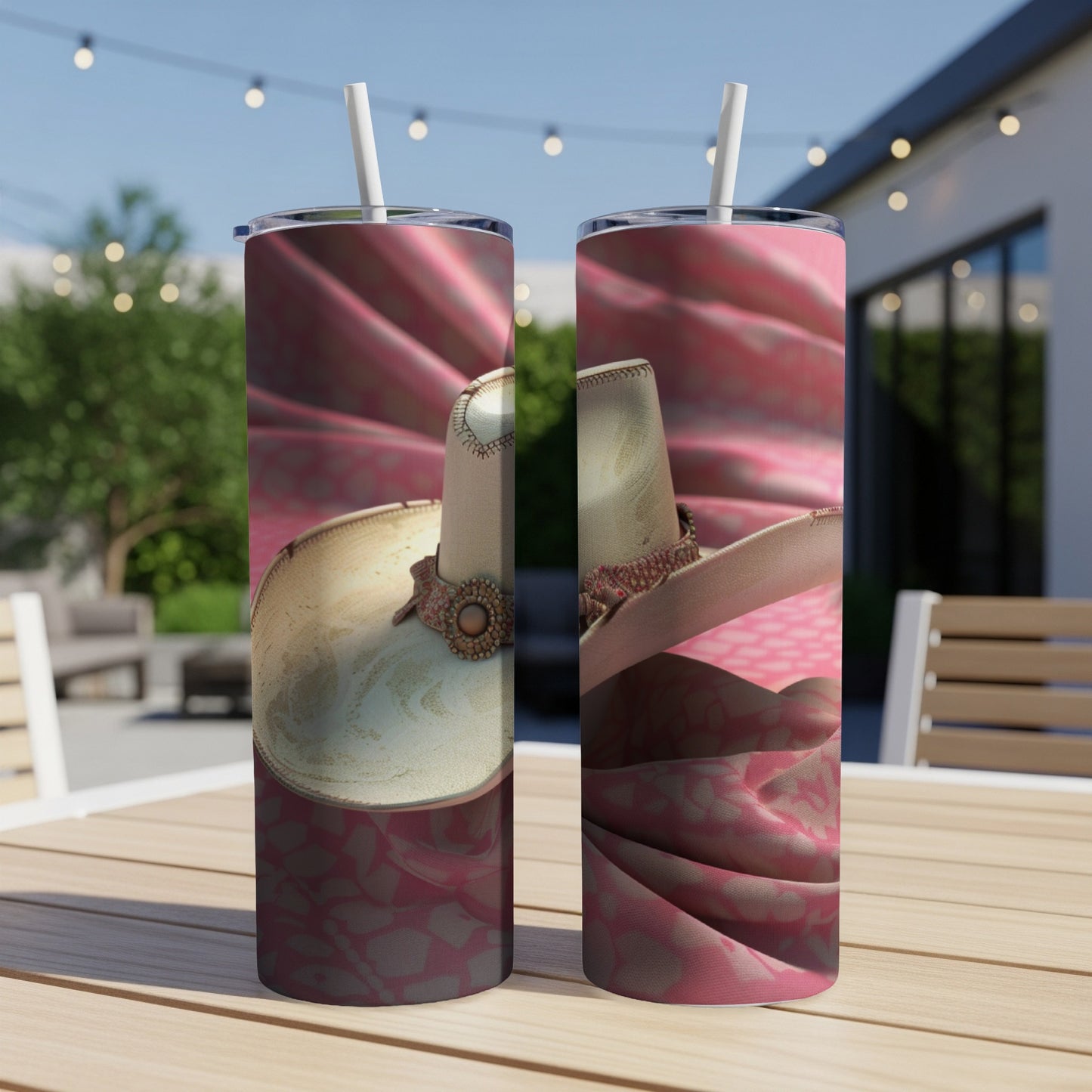 Two tumblers with white cowboy hats and pink patterned fabric on a wooden table.