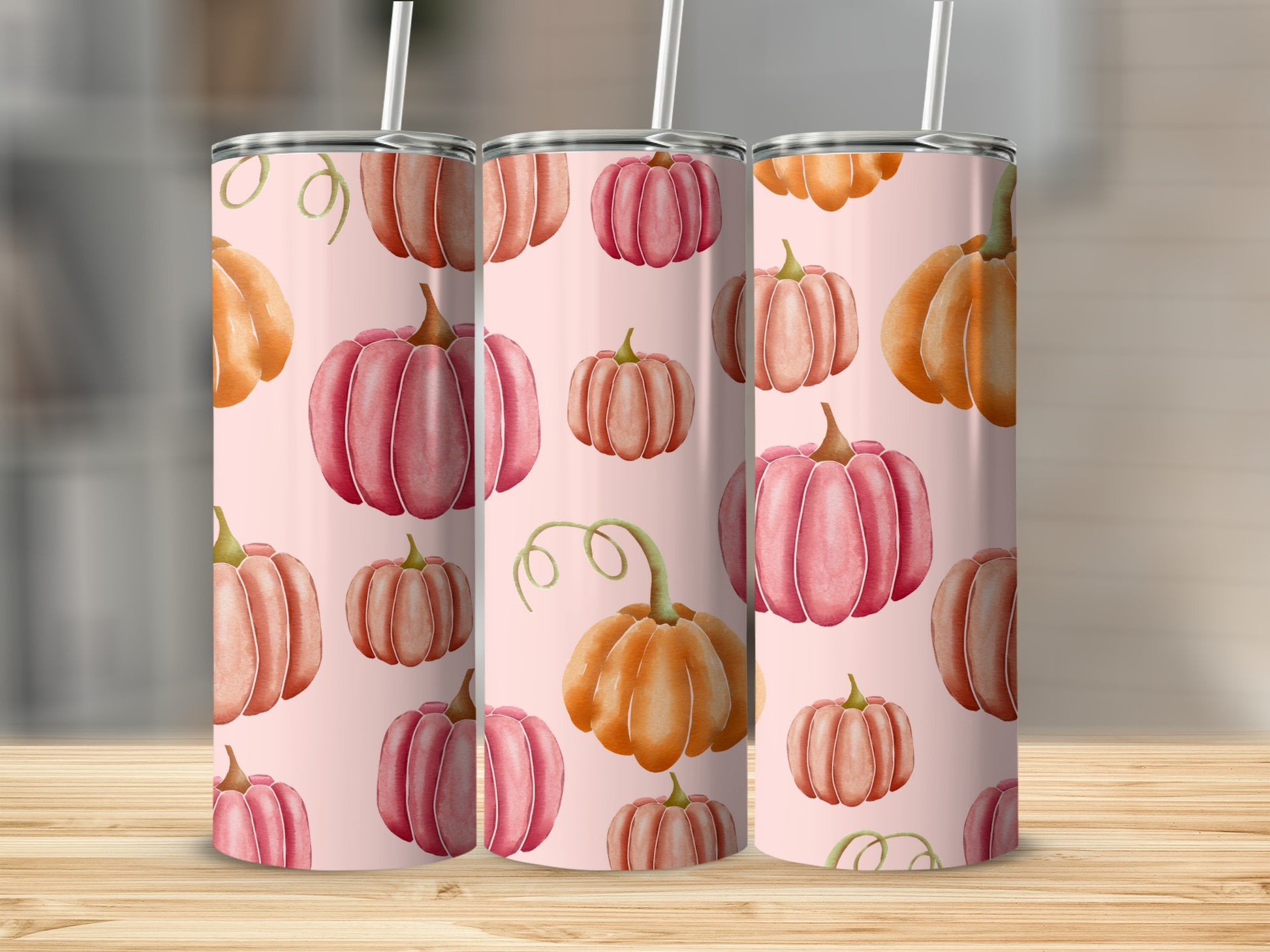 Three tumblers with pink and orange watercolor pumpkins on a pink background.