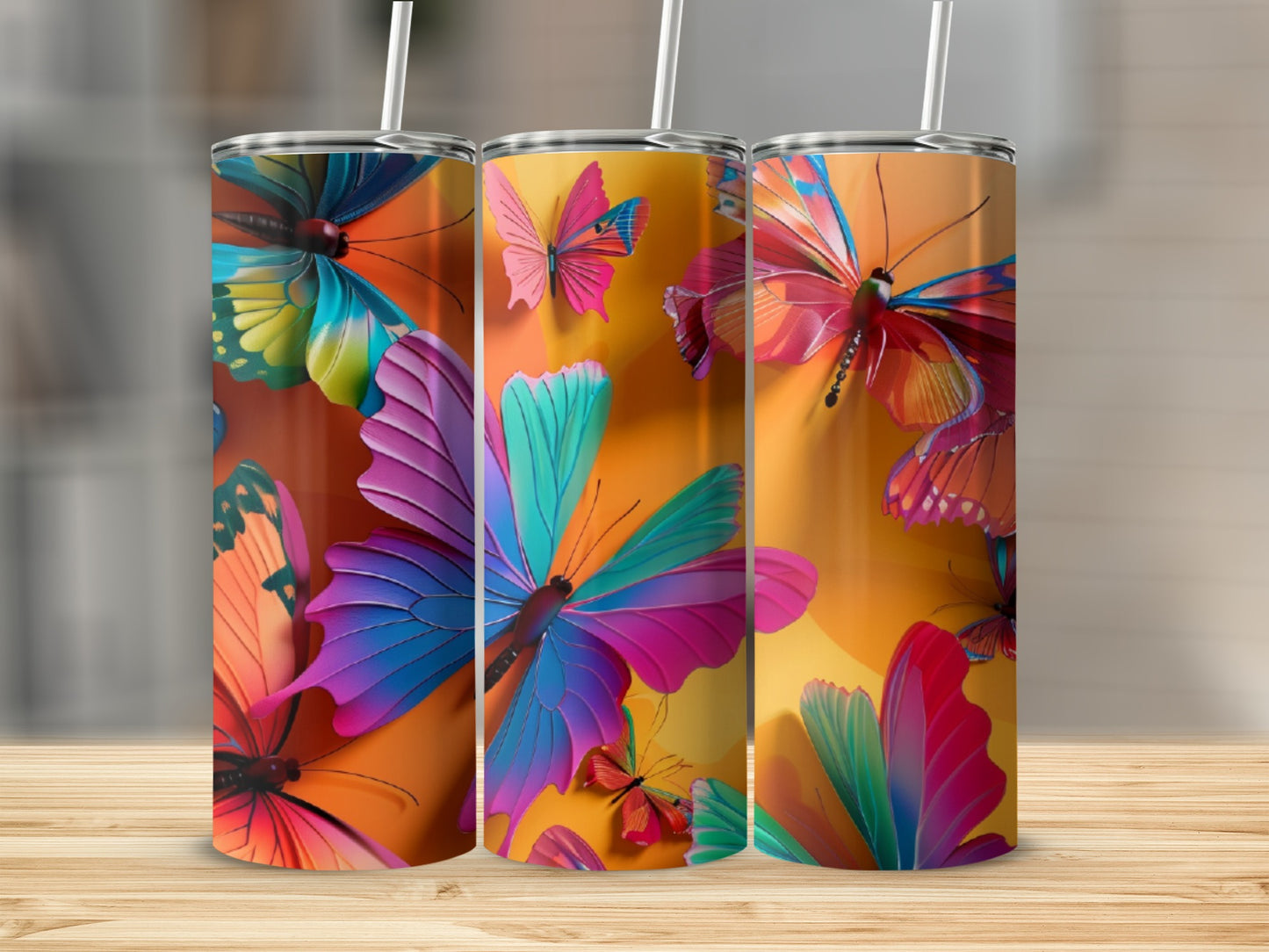 Three tumblers with vibrant butterfly designs on an orange gradient background.