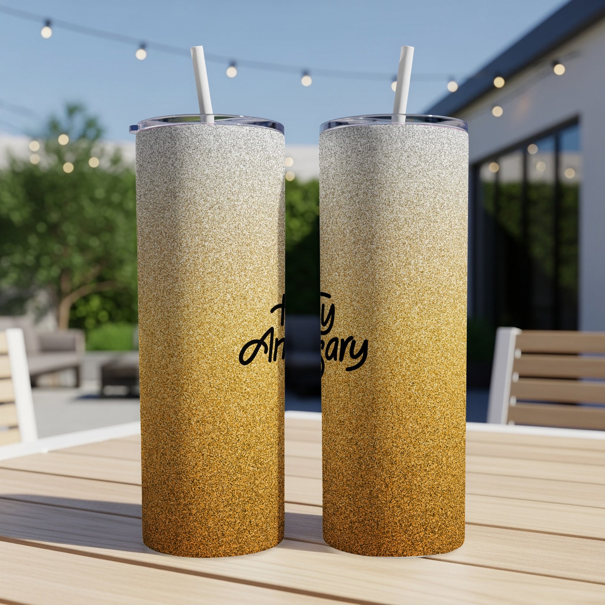 Two glitter-covered tumblers with "Happy Anniversary" text on a patio table.