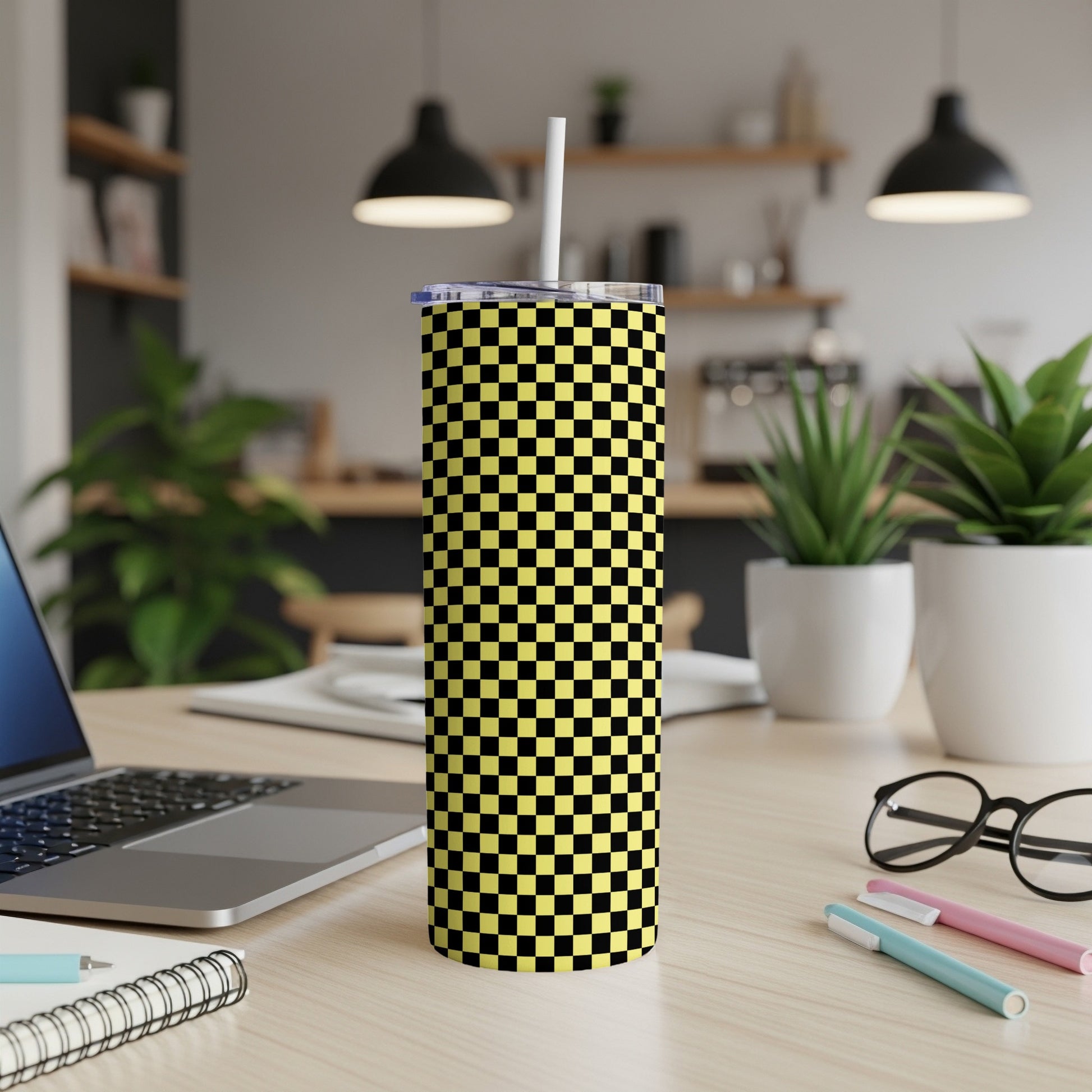Yellow and black checkered tumbler with white straw on desk.