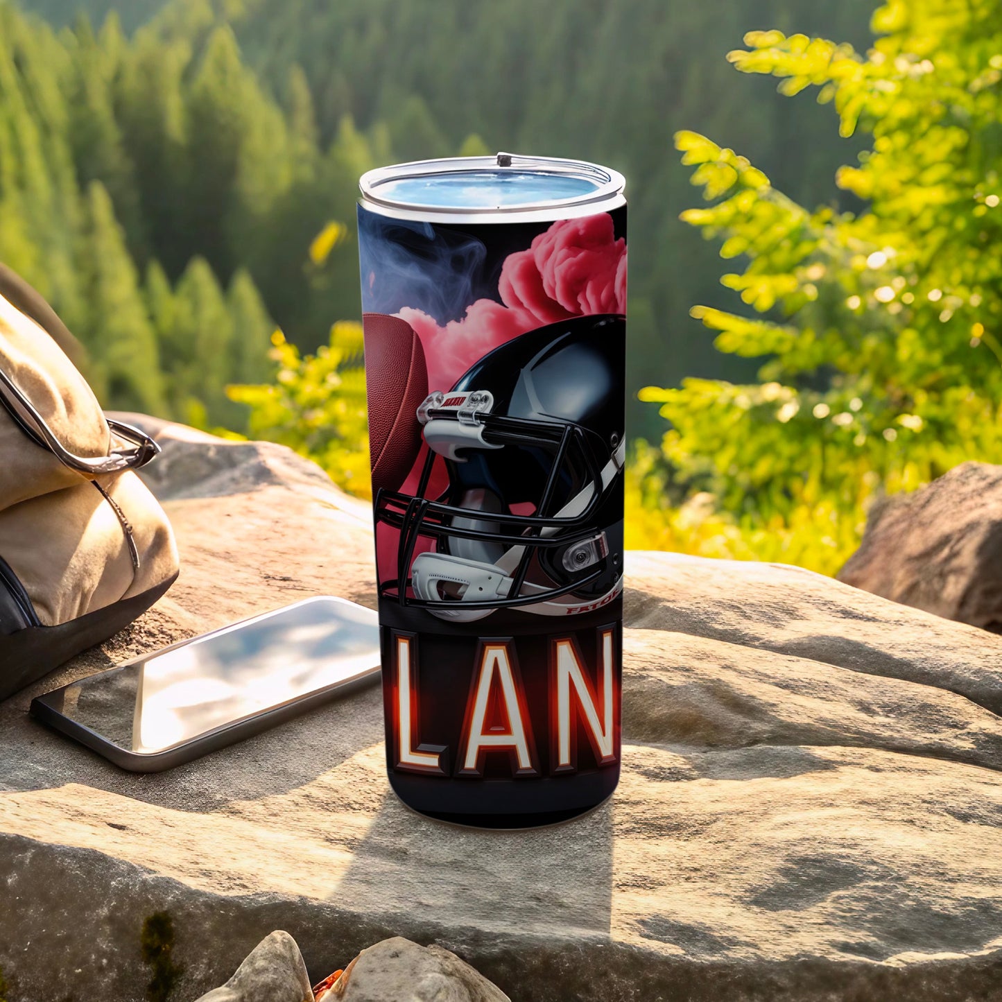 Black tumbler with football helmet and "LAND" graphic, outdoors.