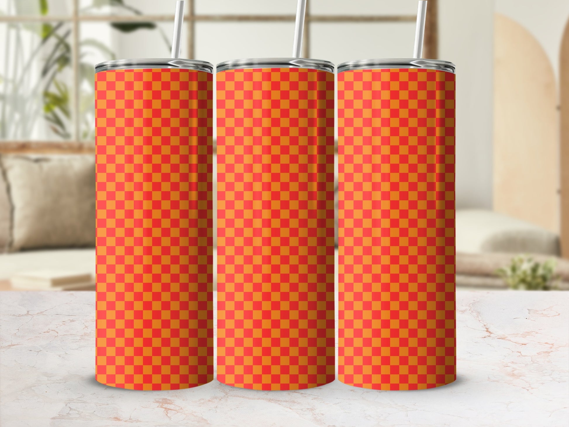 Three orange and red checkered tumblers with straws on a marble surface.