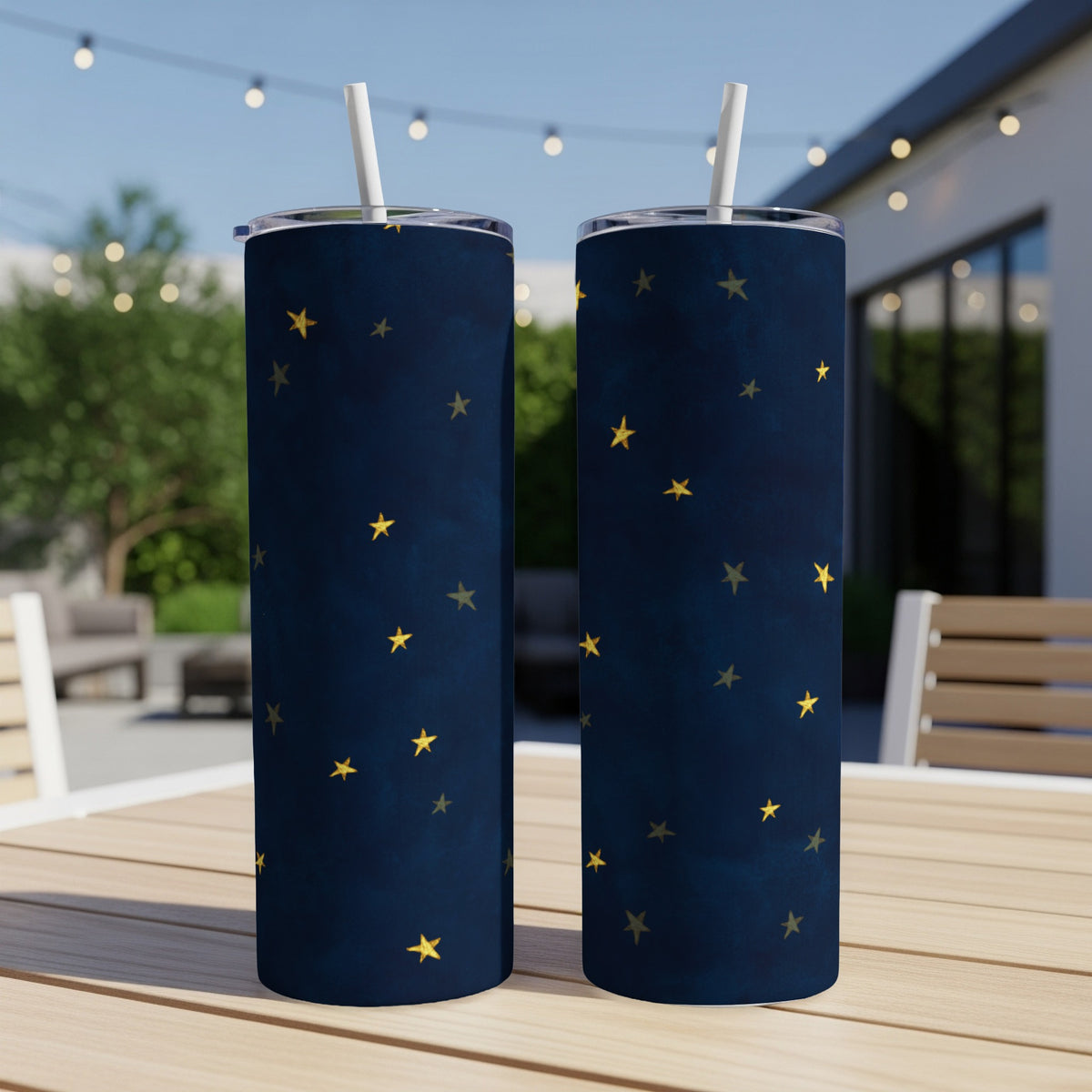 Two dark blue tumblers with a scattered gold star pattern and white straws.