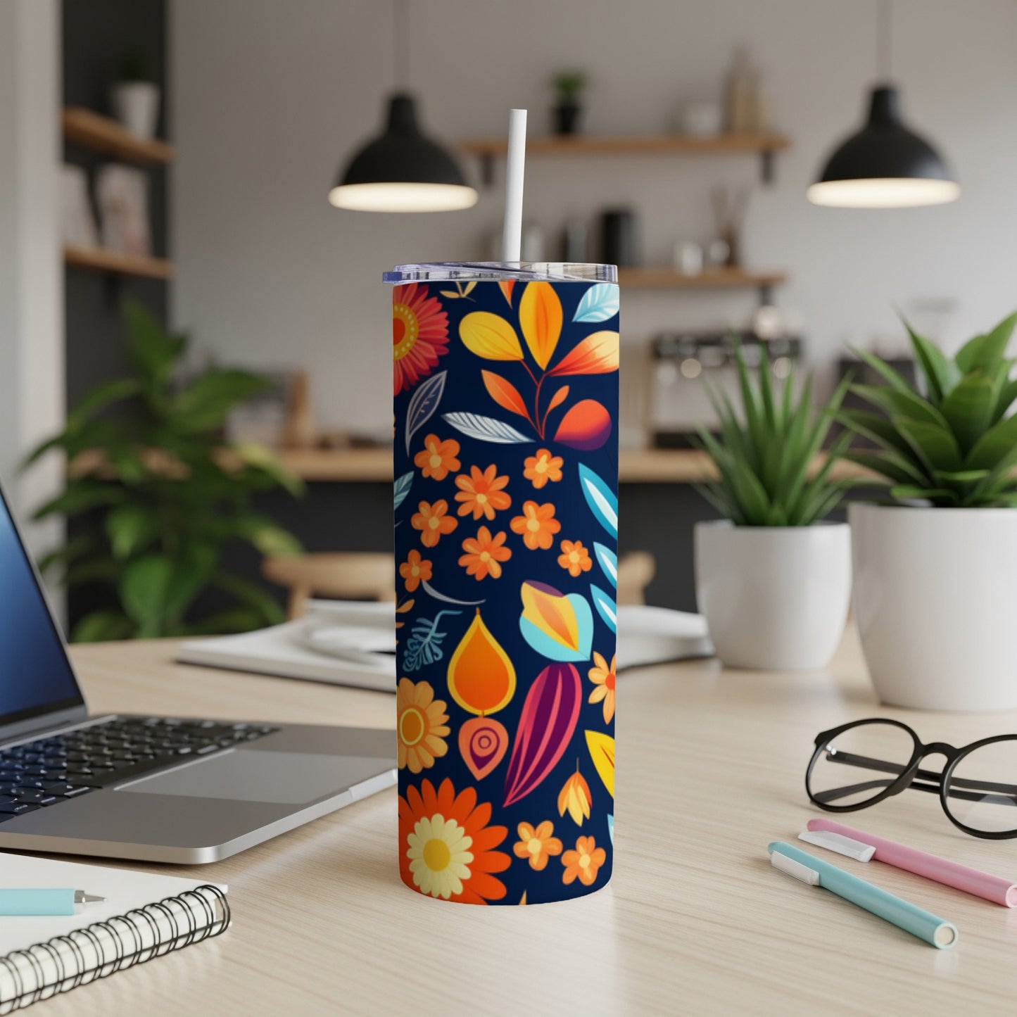 Dark blue tumbler with vibrant floral and leaf patterns and a white straw.