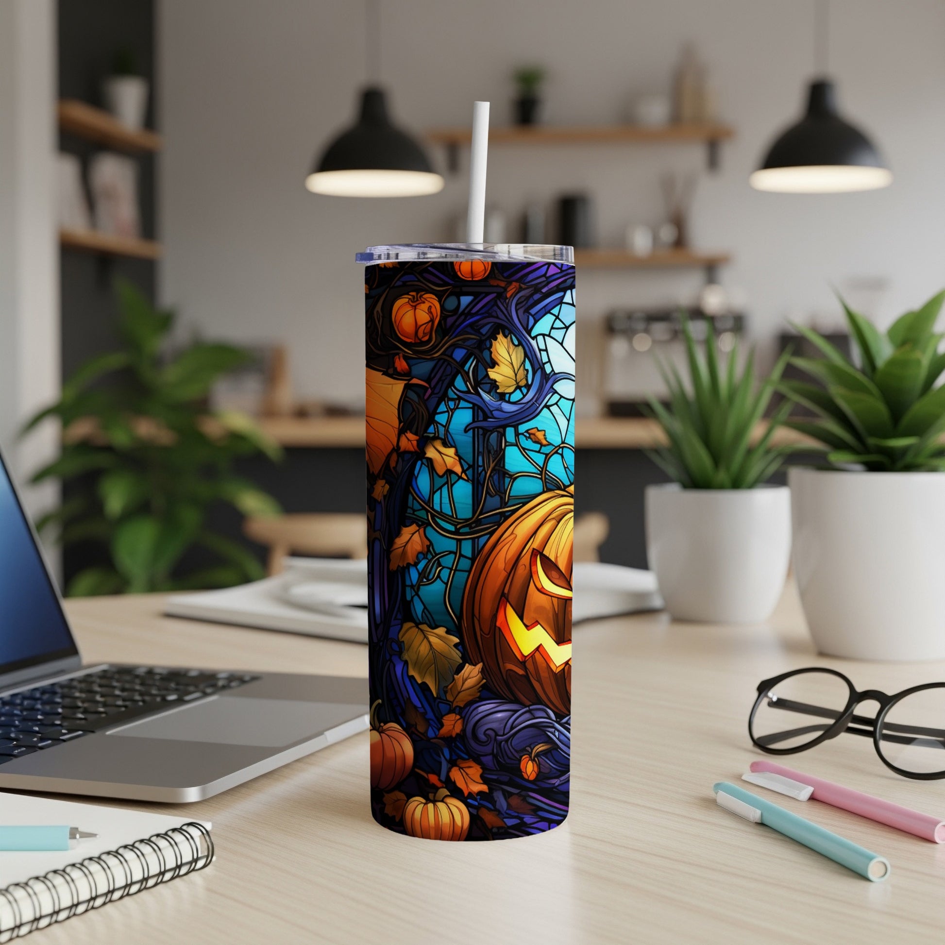 Halloween tumbler with jack-o'-lanterns, pumpkins, and gothic swirls on a desk.