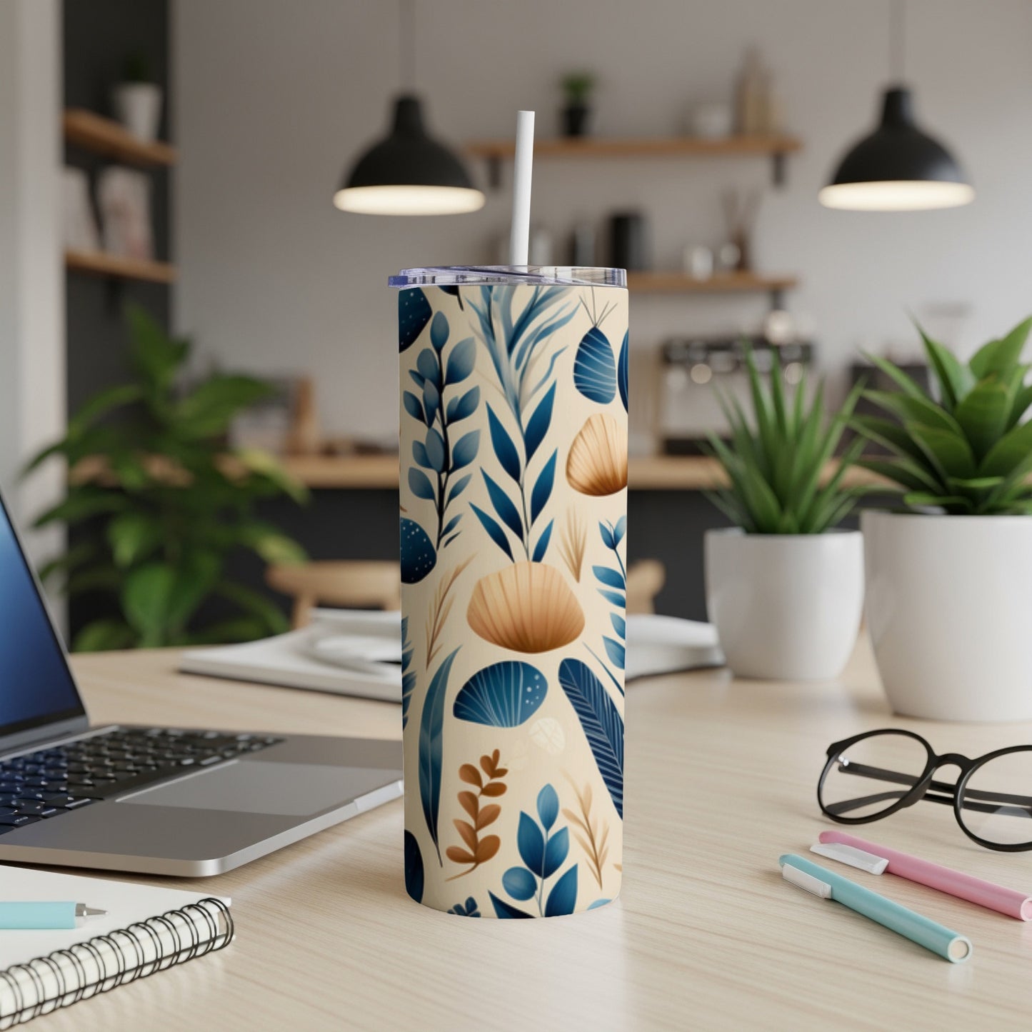 Tan and blue floral print skinny tumbler with straw on desk.