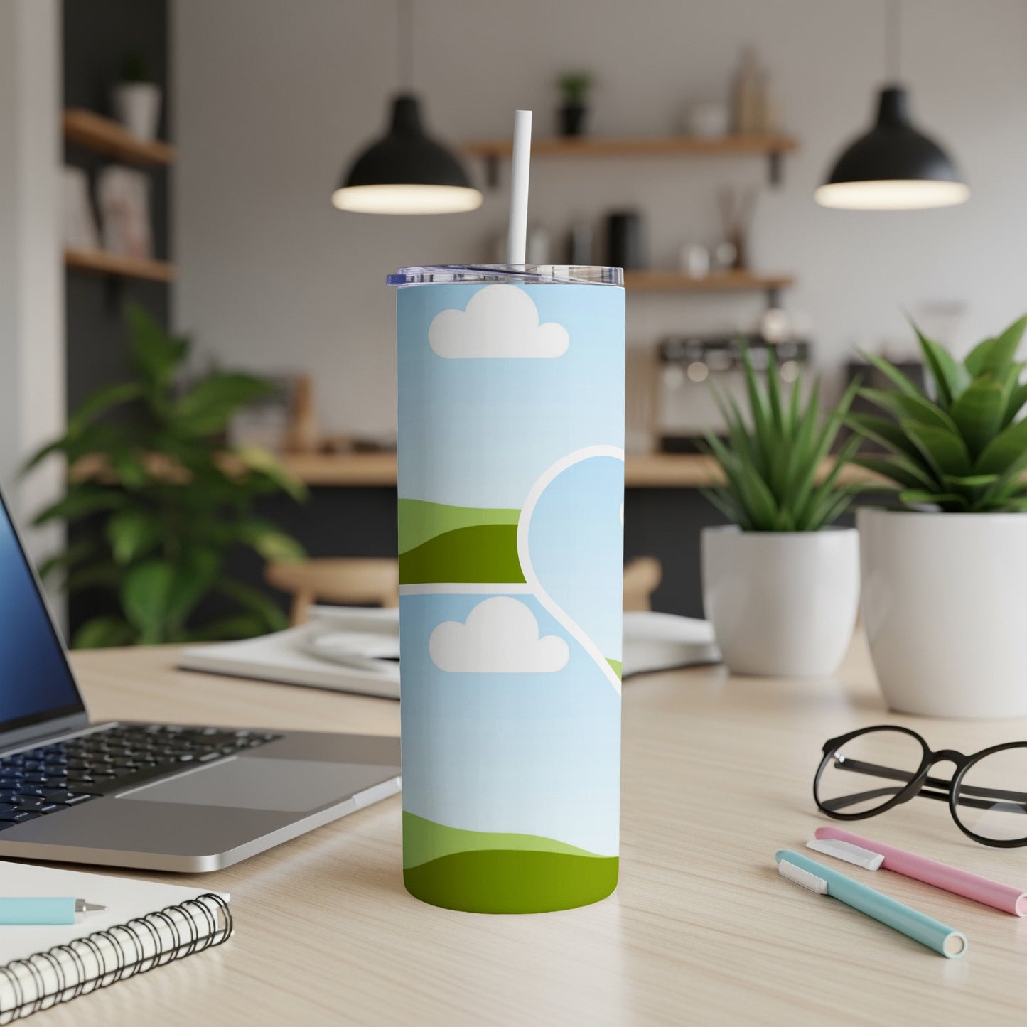 Tall tumbler with a sky, clouds, and green hills design and a straw.