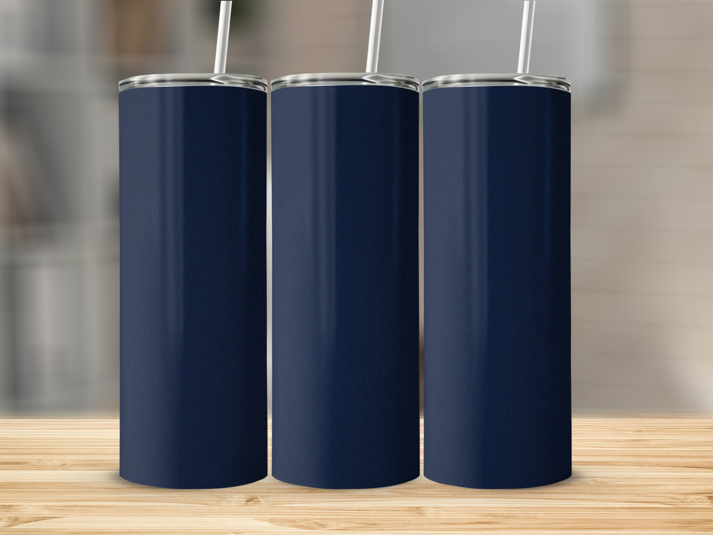 Three navy blue tumblers with white straws stand on a wooden surface.