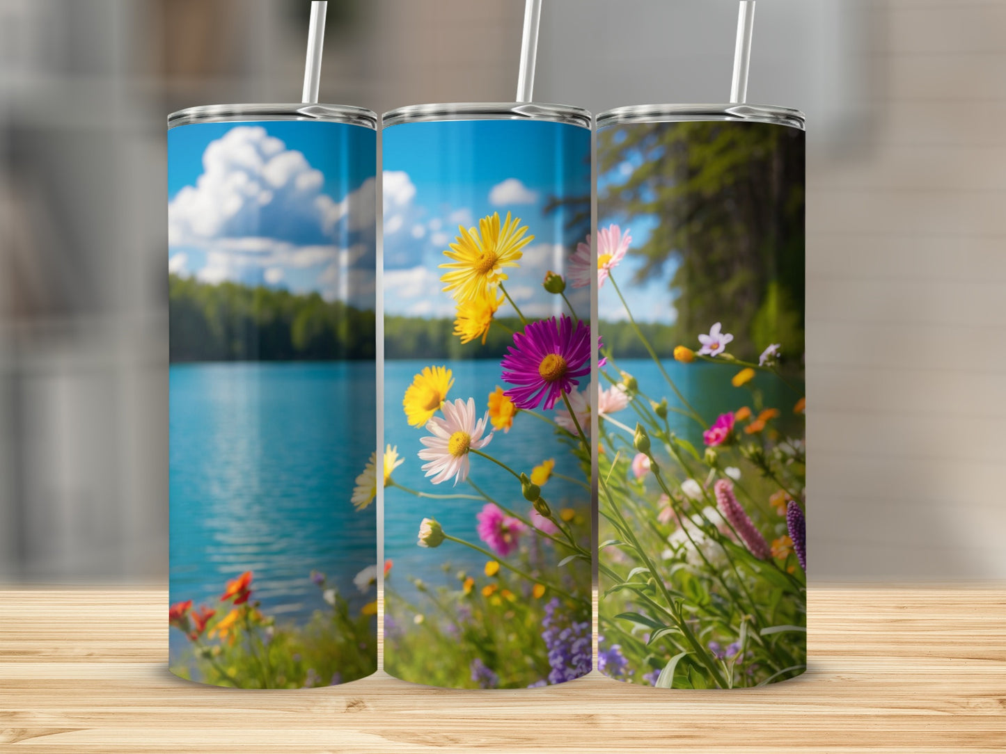 Three tumblers with a floral lakeside scene on a wooden surface.