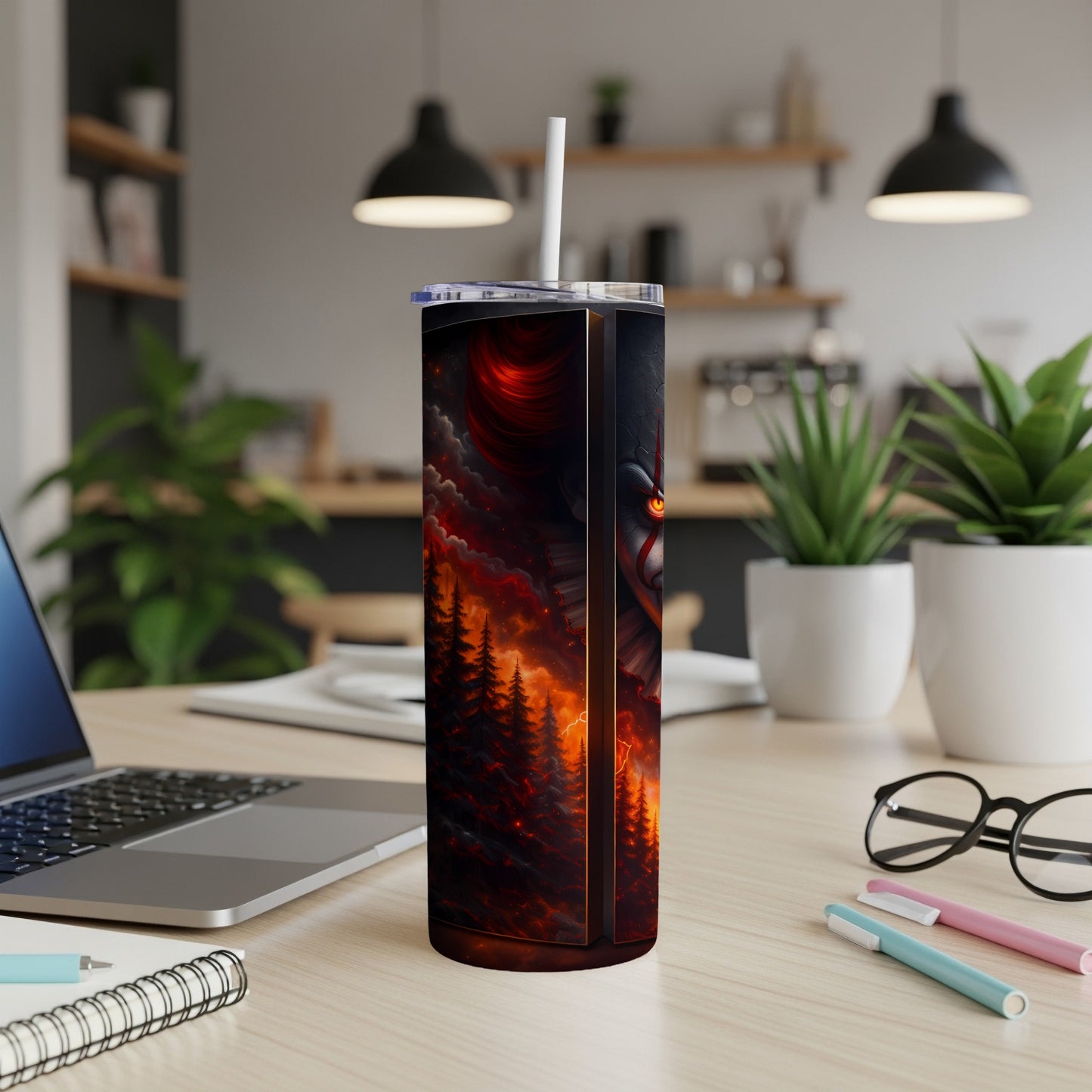 Tumbler with fiery forest and clown face design, with a white straw.