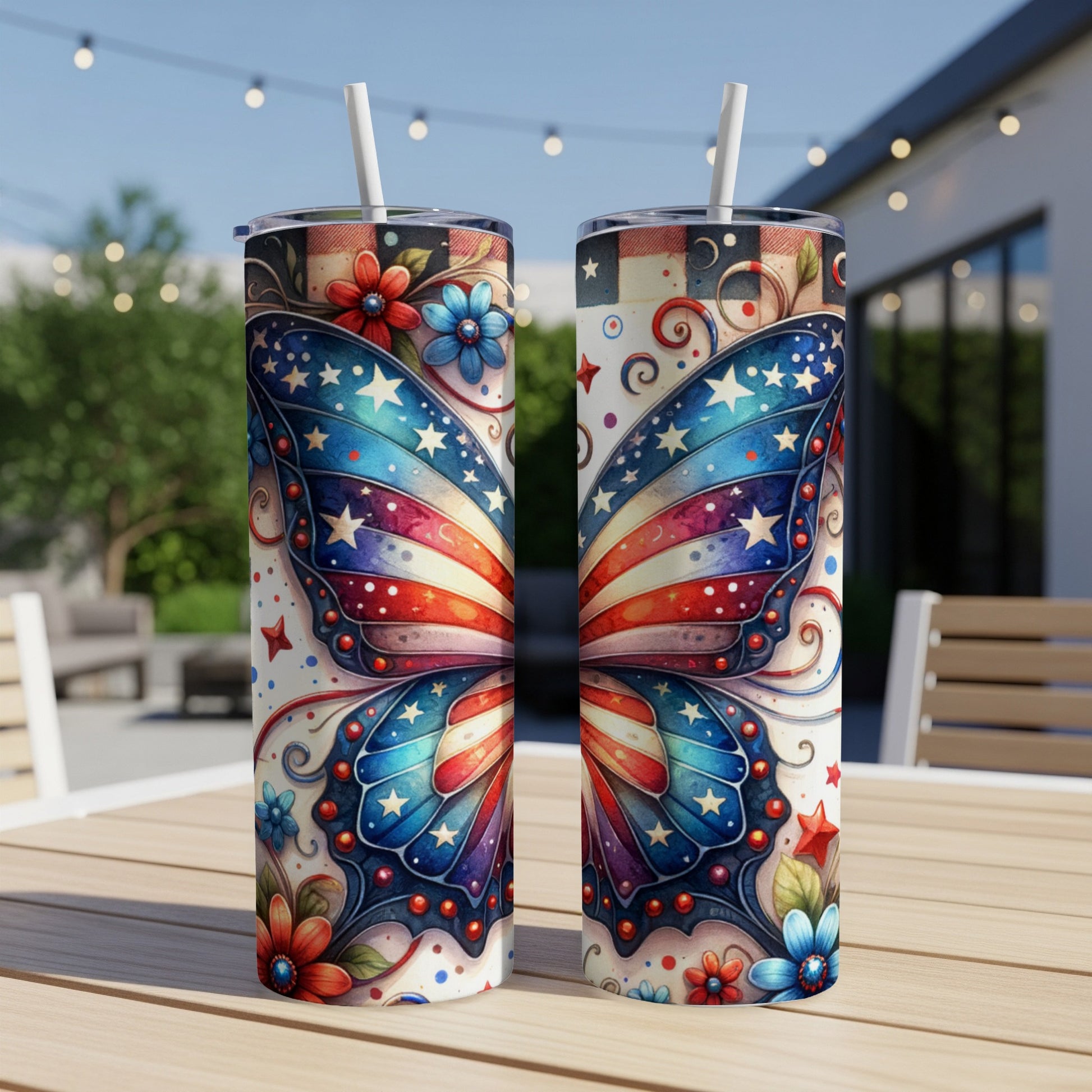 Two patriotic butterfly wing patterned tumblers with straws on a table.