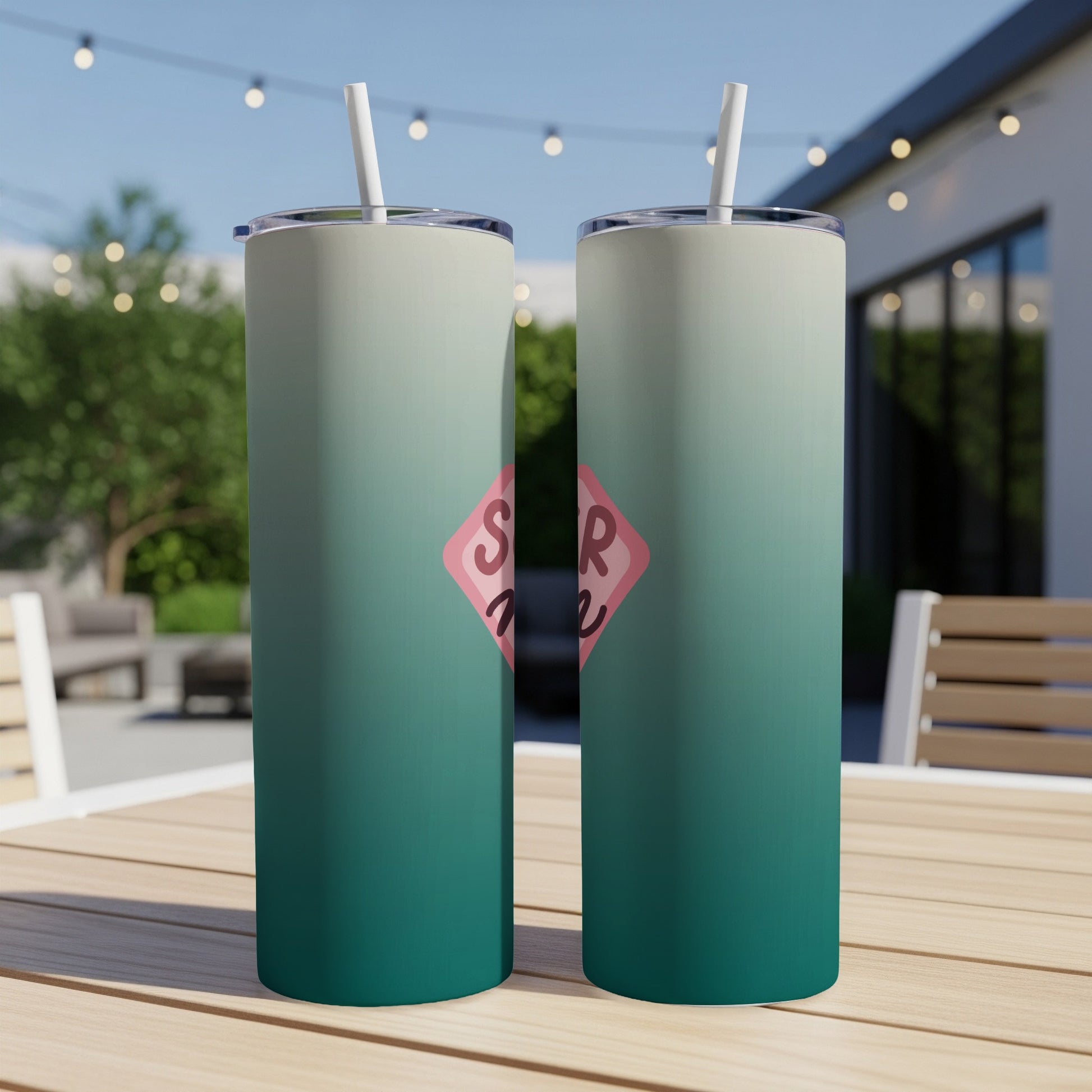 Two teal and white ombre tumblers with pink SR logo on a wooden table.