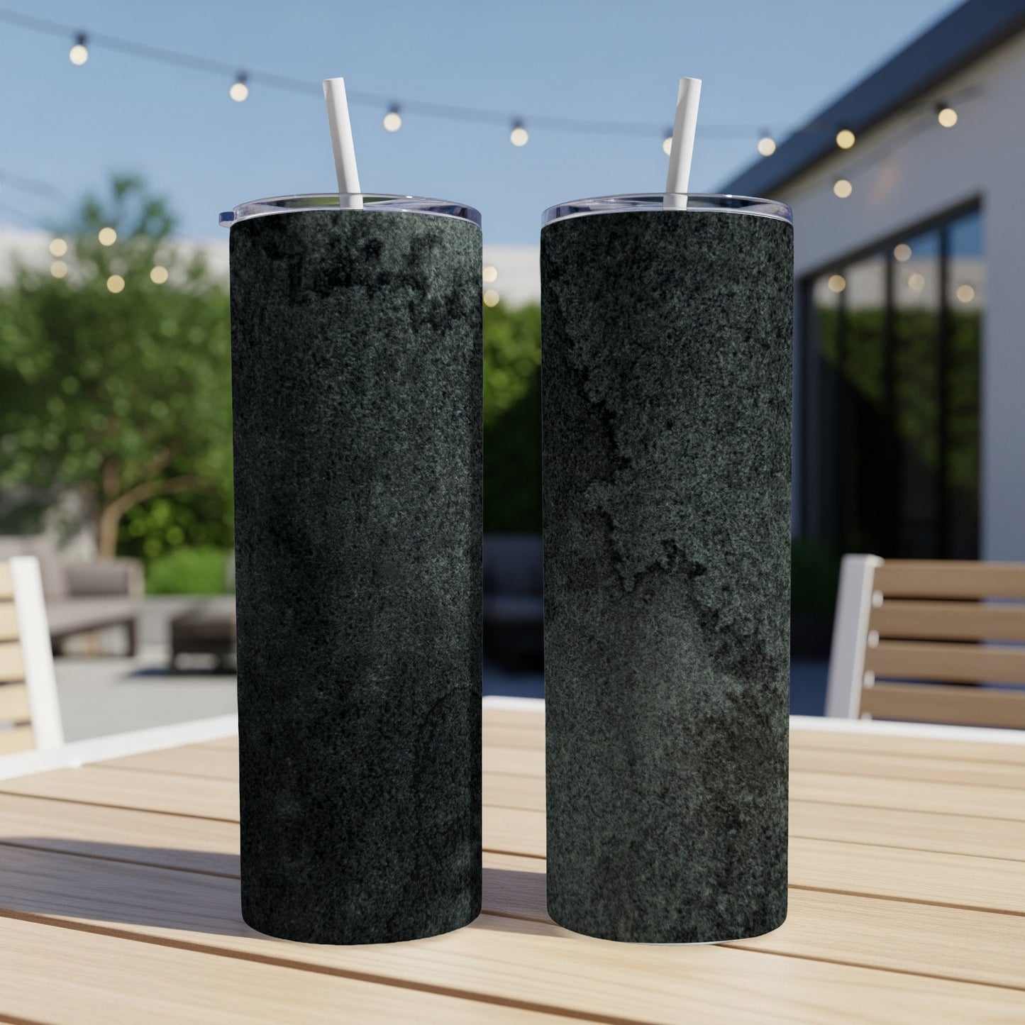 Two dark gray textured tumblers with white straws on a wooden table.