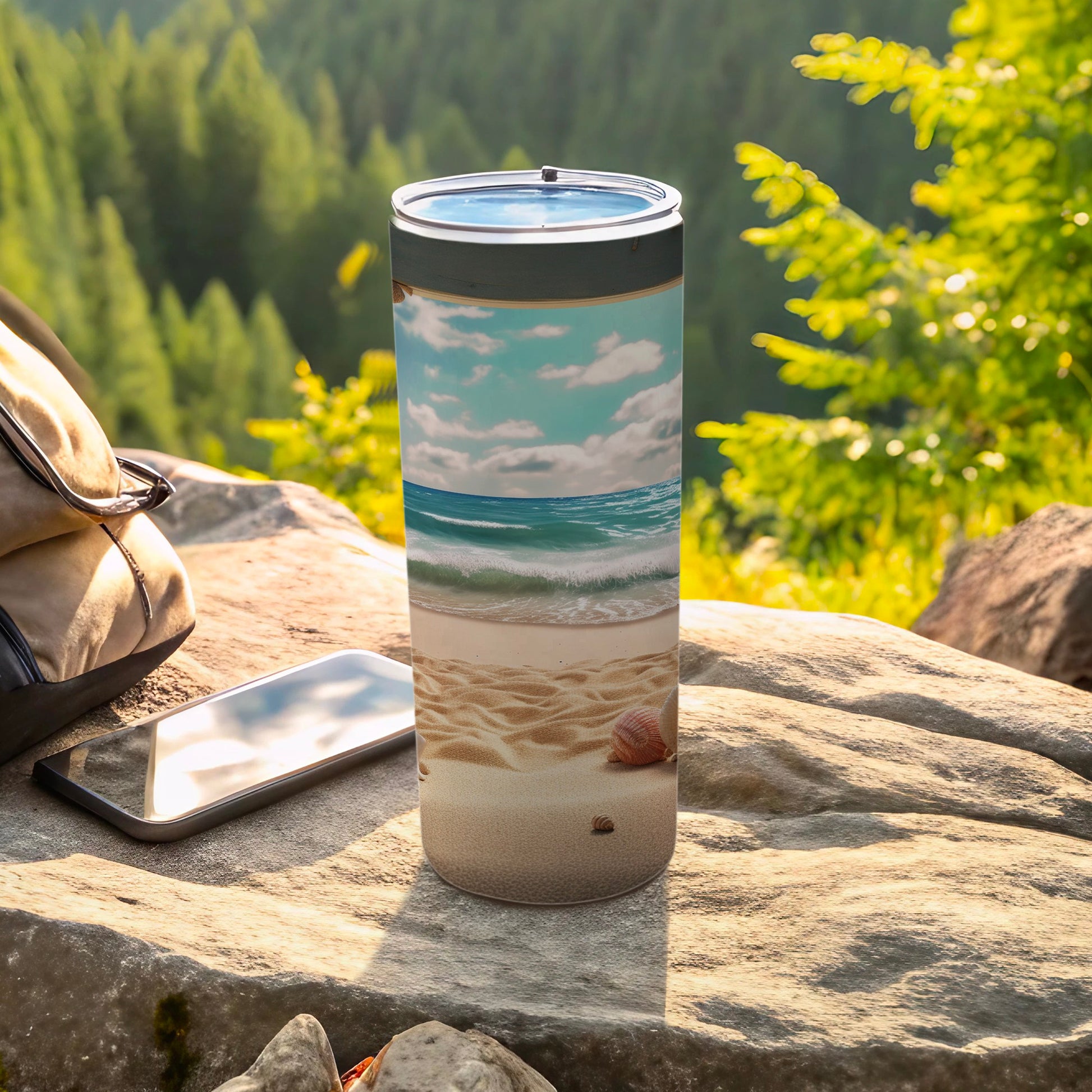 Tall tumbler with a beach scene and ocean waves, next to a phone.