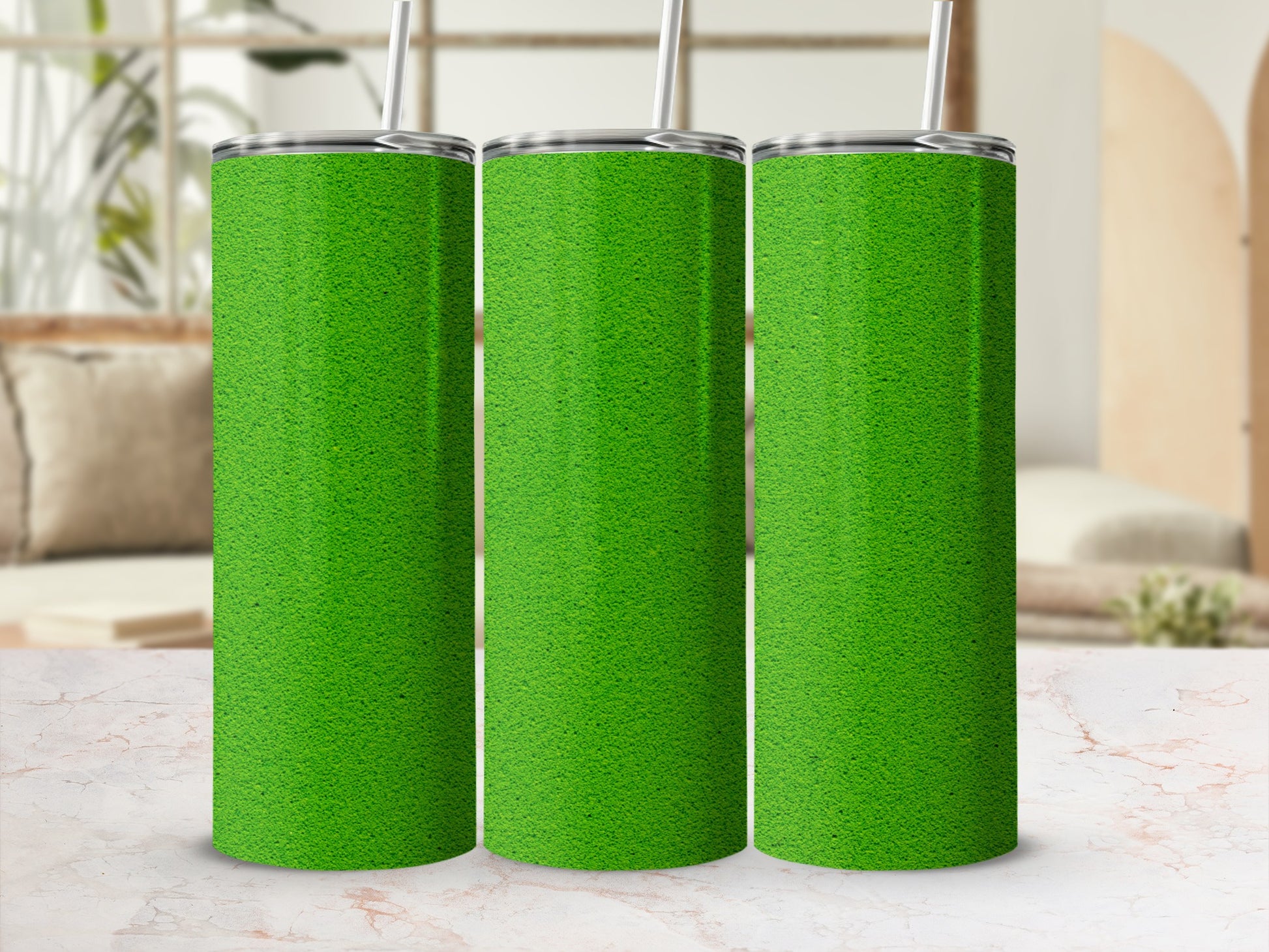 Three green tumblers with straws displayed on a marble surface.