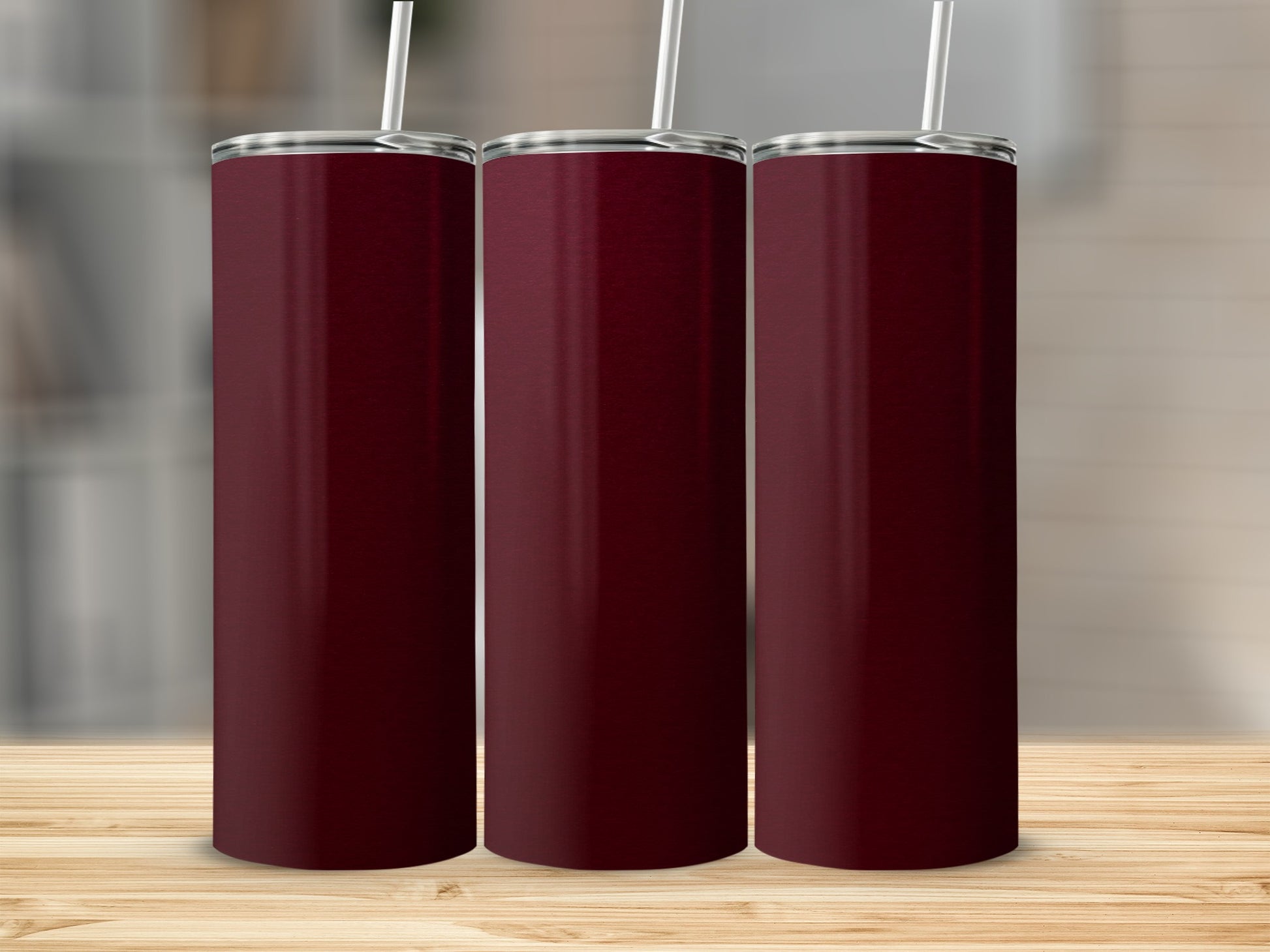 Three tall, dark red tumblers with white straws on a wooden surface.