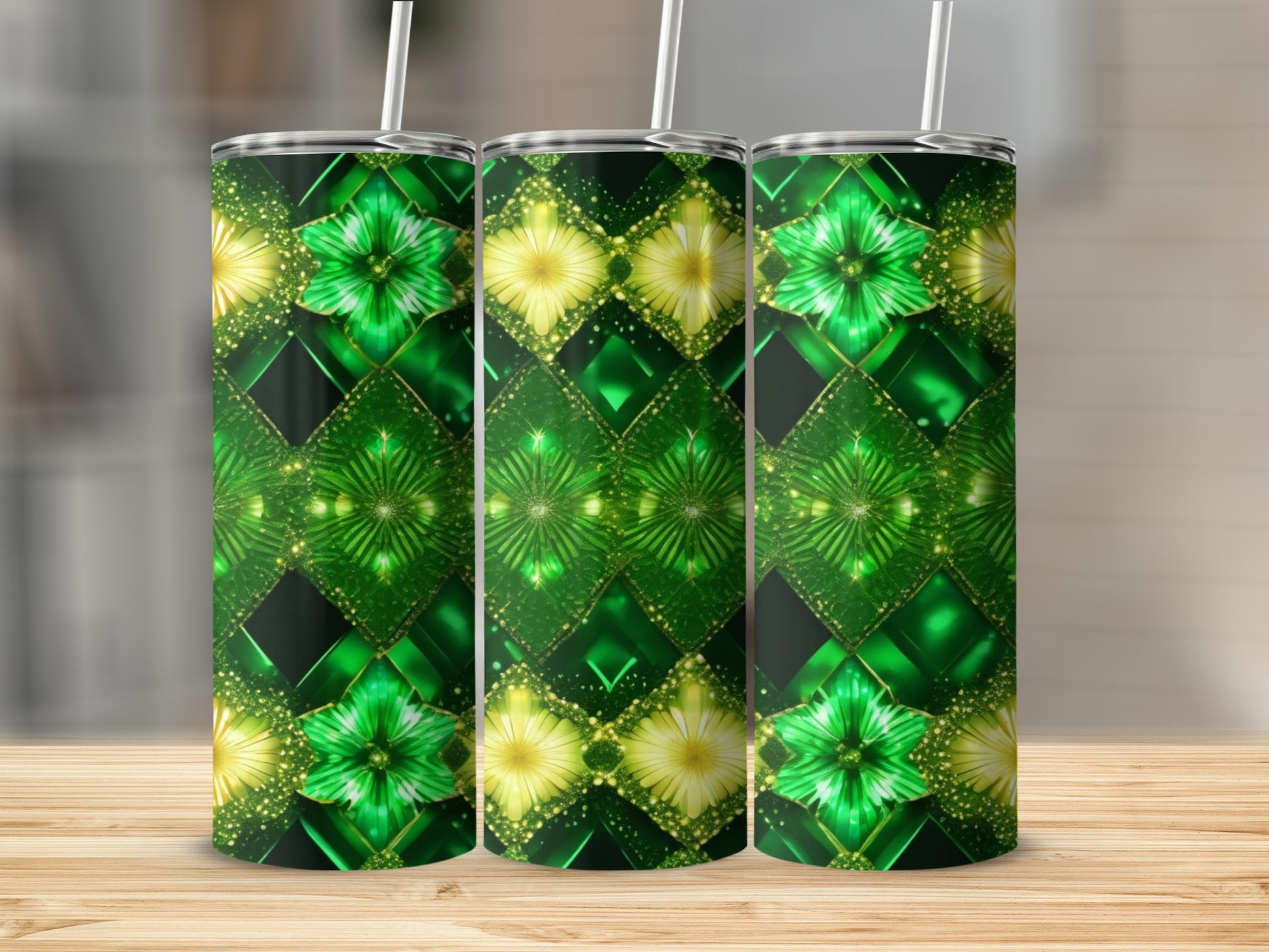 Three green and gold floral patterned tumblers with straws stand on a wooden surface.