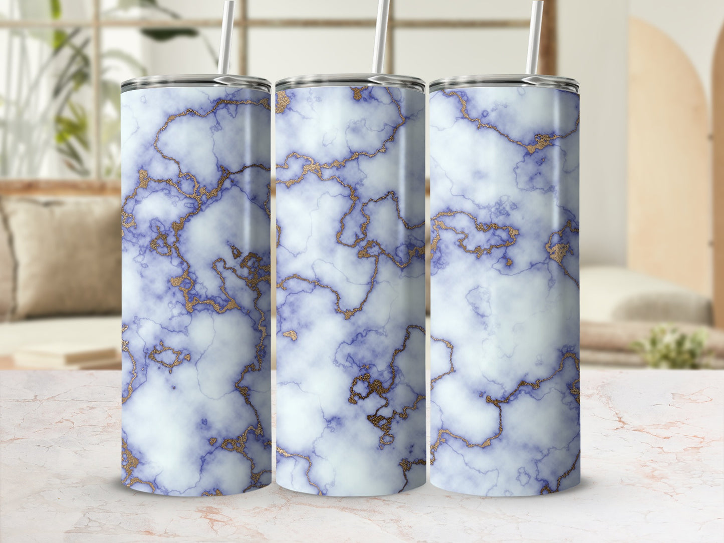 Three white marble tumblers with gold veining and a straw.