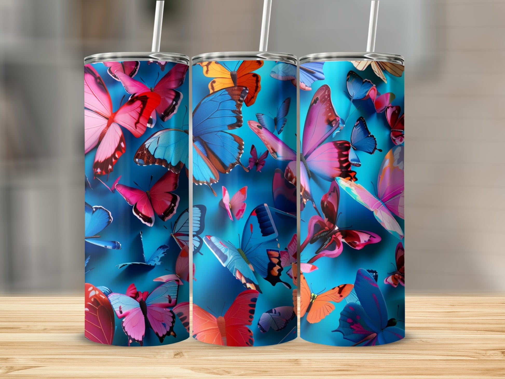Three tumblers with colorful butterflies on a blue background.