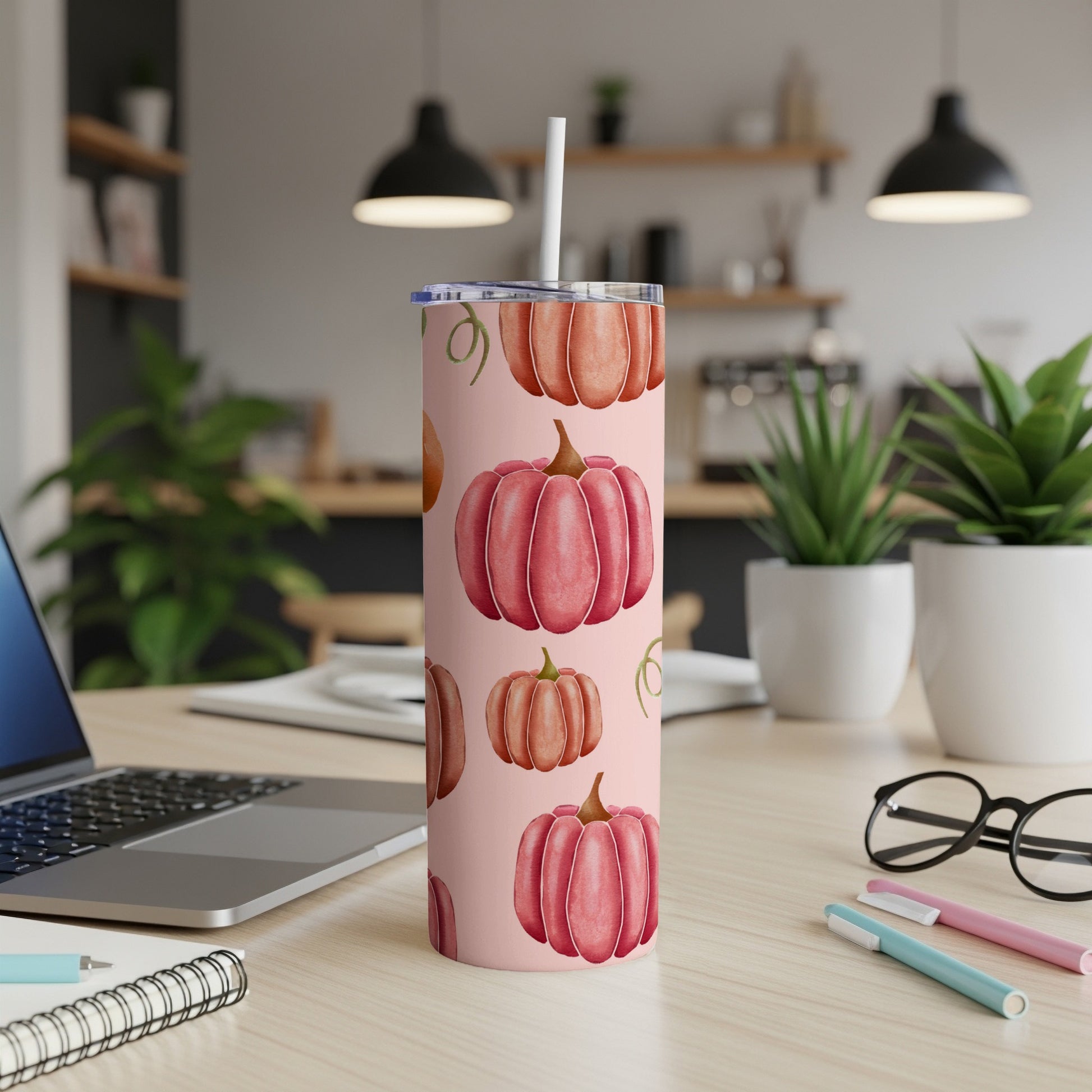 Pink tumbler with a pattern of orange and pink pumpkins and a straw.