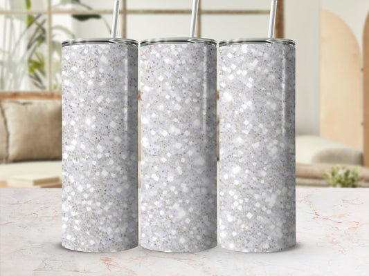 Three speckled glitter tumblers with straws stand on a marble surface.