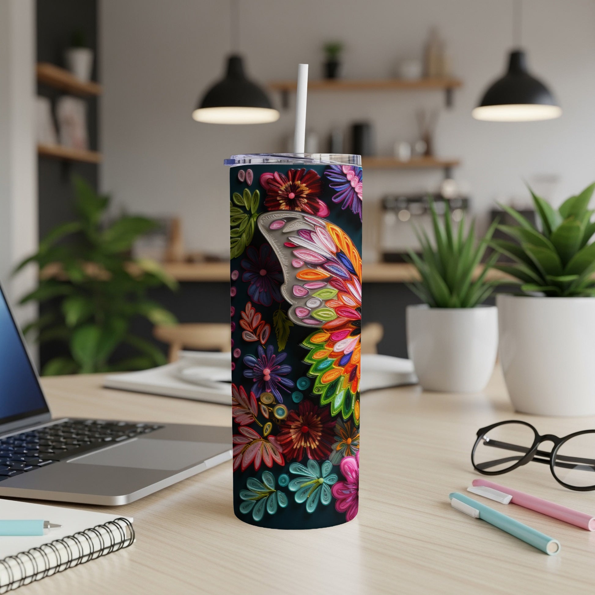 Tall floral tumbler with butterfly wing design and straw on a desk.
