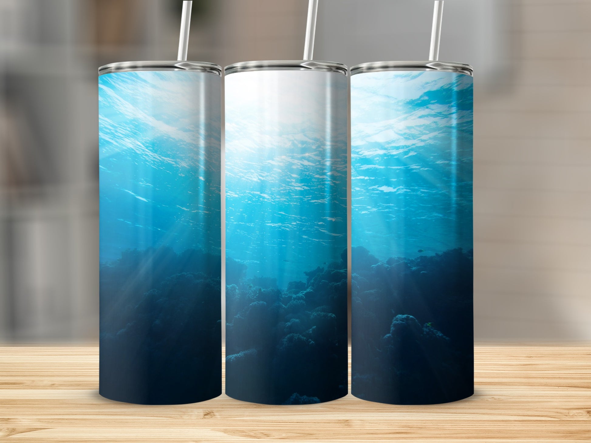 Underwater scene with coral and sunbeams, on three tumblers.