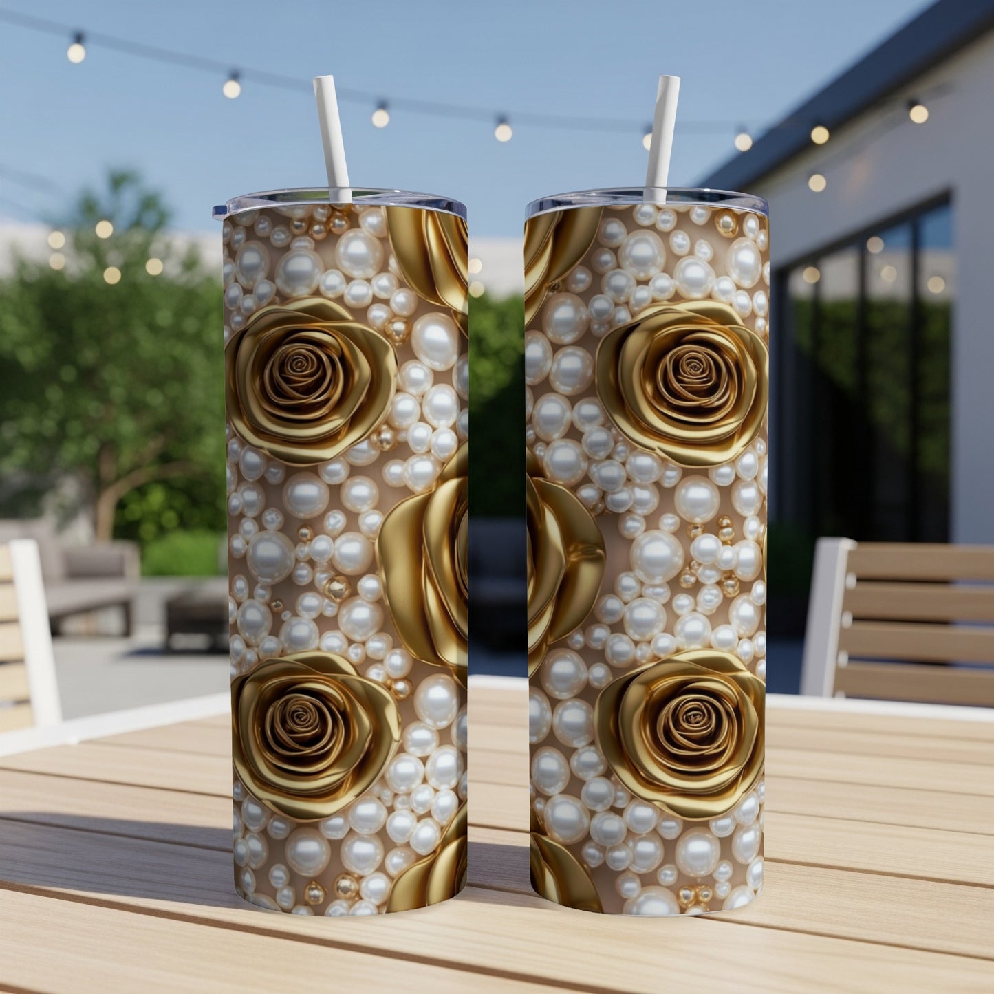 Two gold rose and pearl patterned tumblers on a table outdoors.