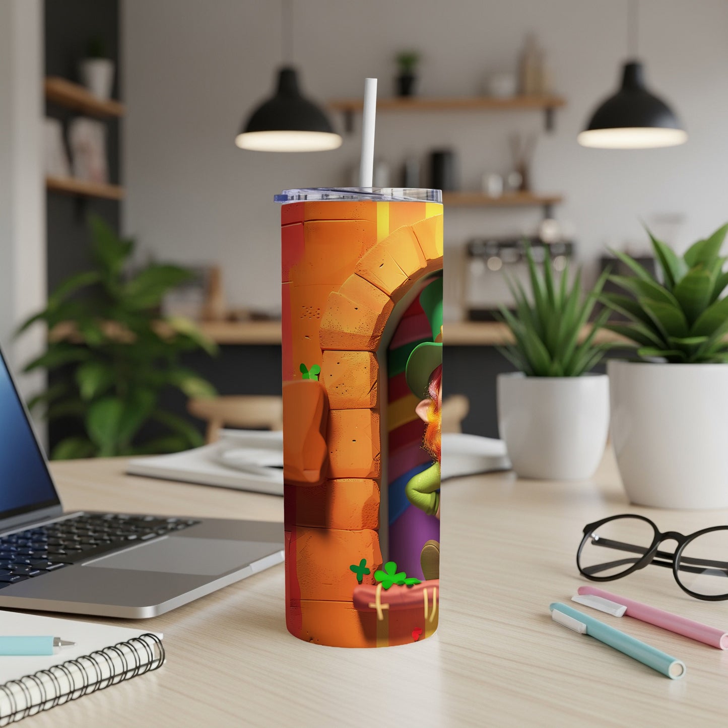 Leprechaun and shamrocks on an orange tumbler with a straw, on a desk.
