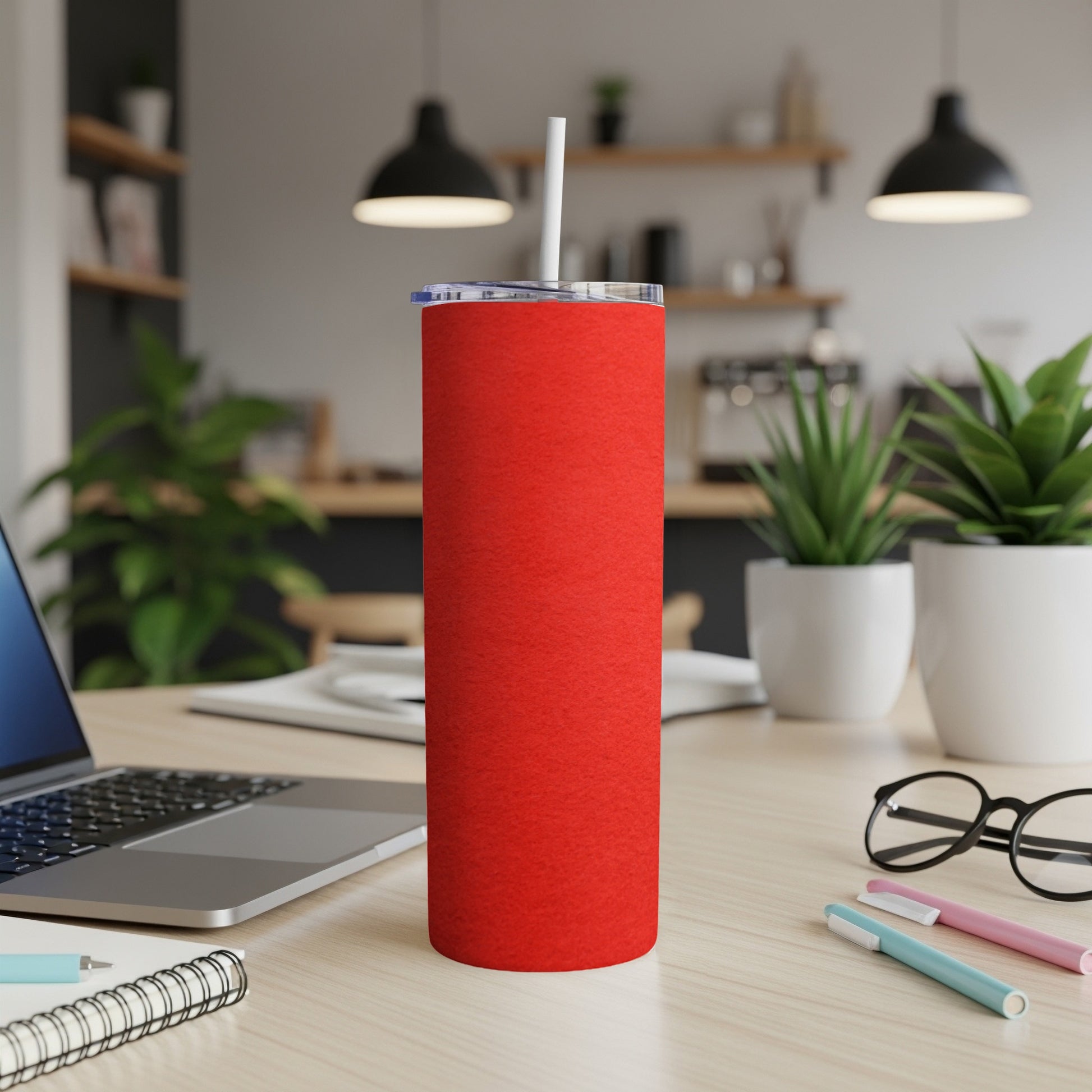 Red stainless steel tumbler with a white straw on a wooden desk.
