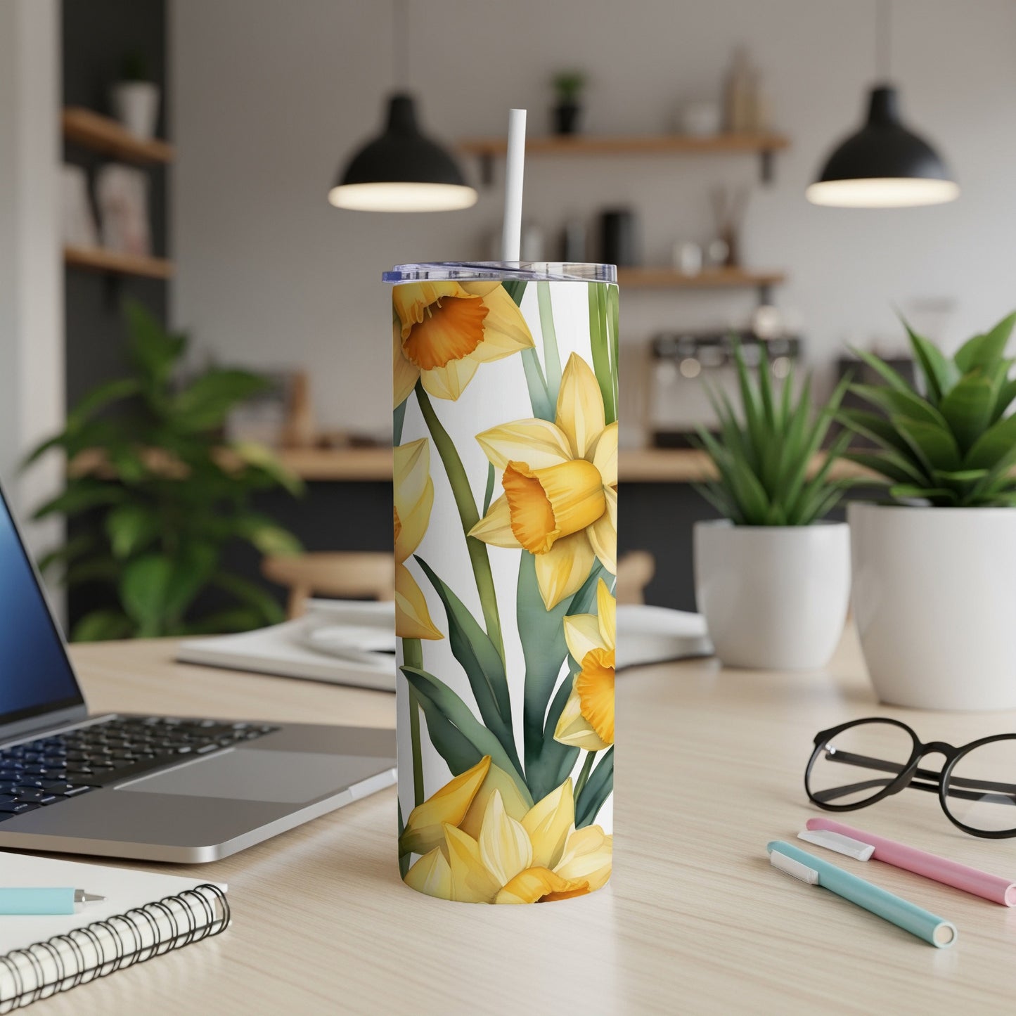 Yellow daffodils and green leaves pattern on a white tumbler with a straw.