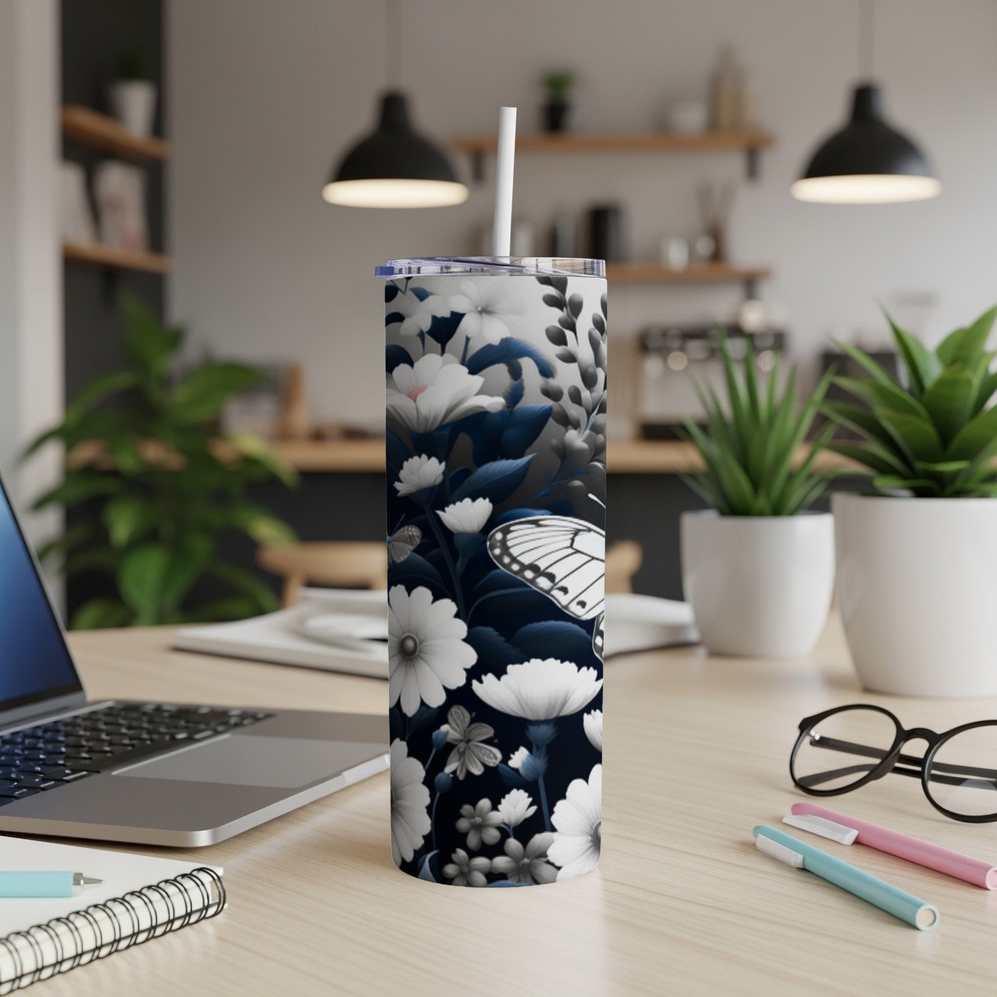 White butterfly and floral pattern on a black skinny tumbler with a straw.