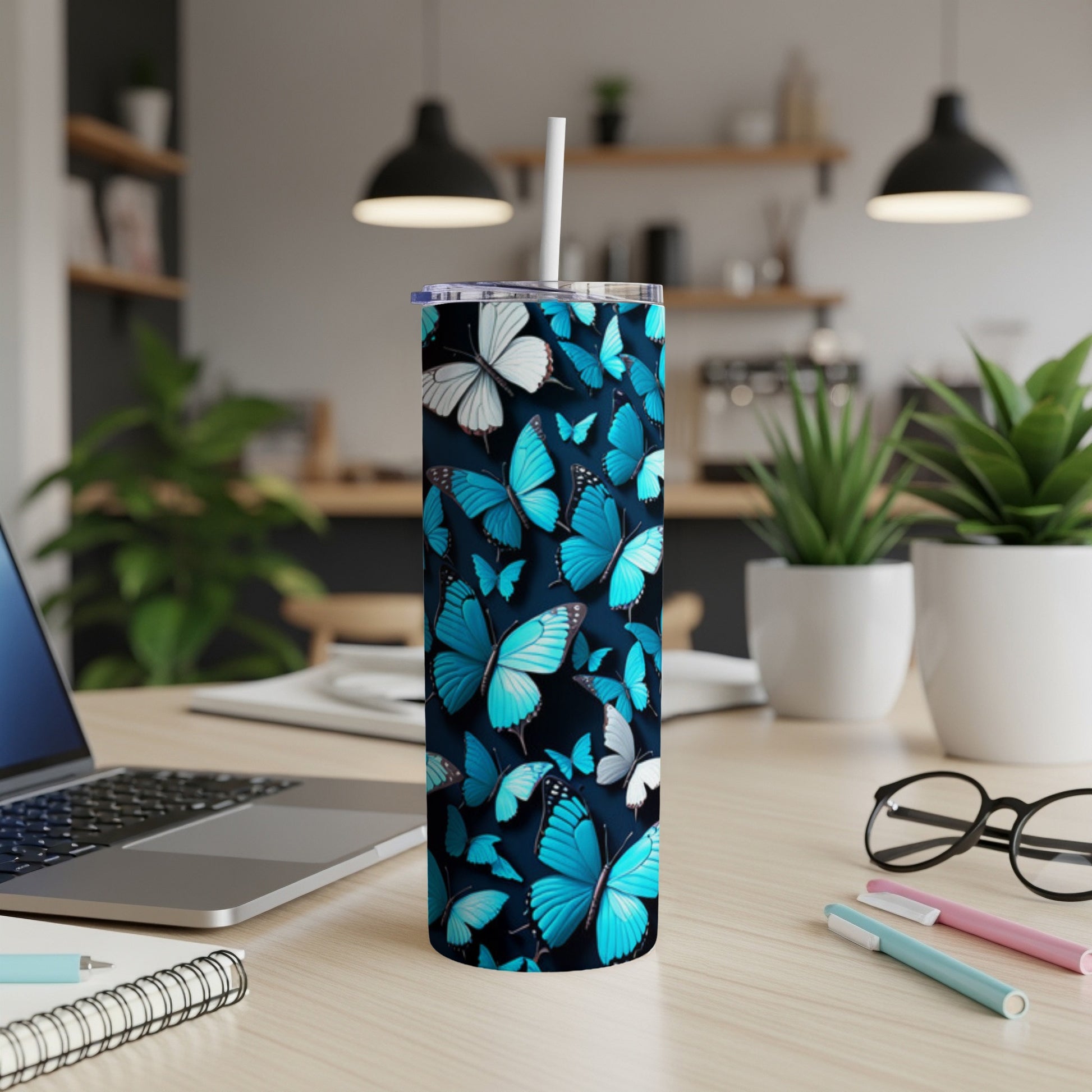 Blue butterflies cover a white tumbler with a straw, on a desk.