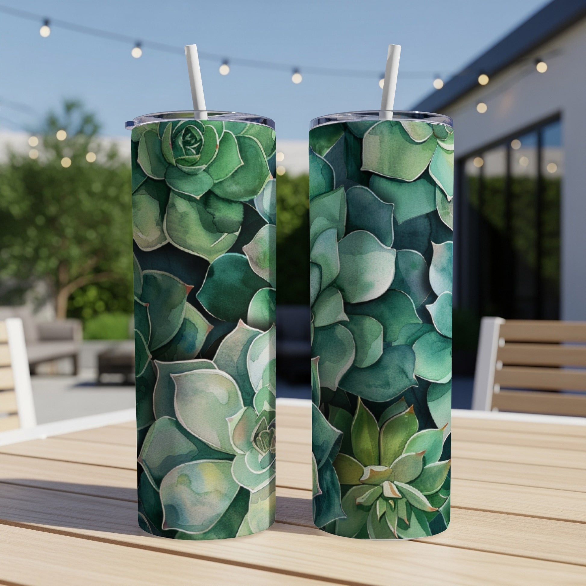 Two green succulent-patterned tumblers on a table outdoors.