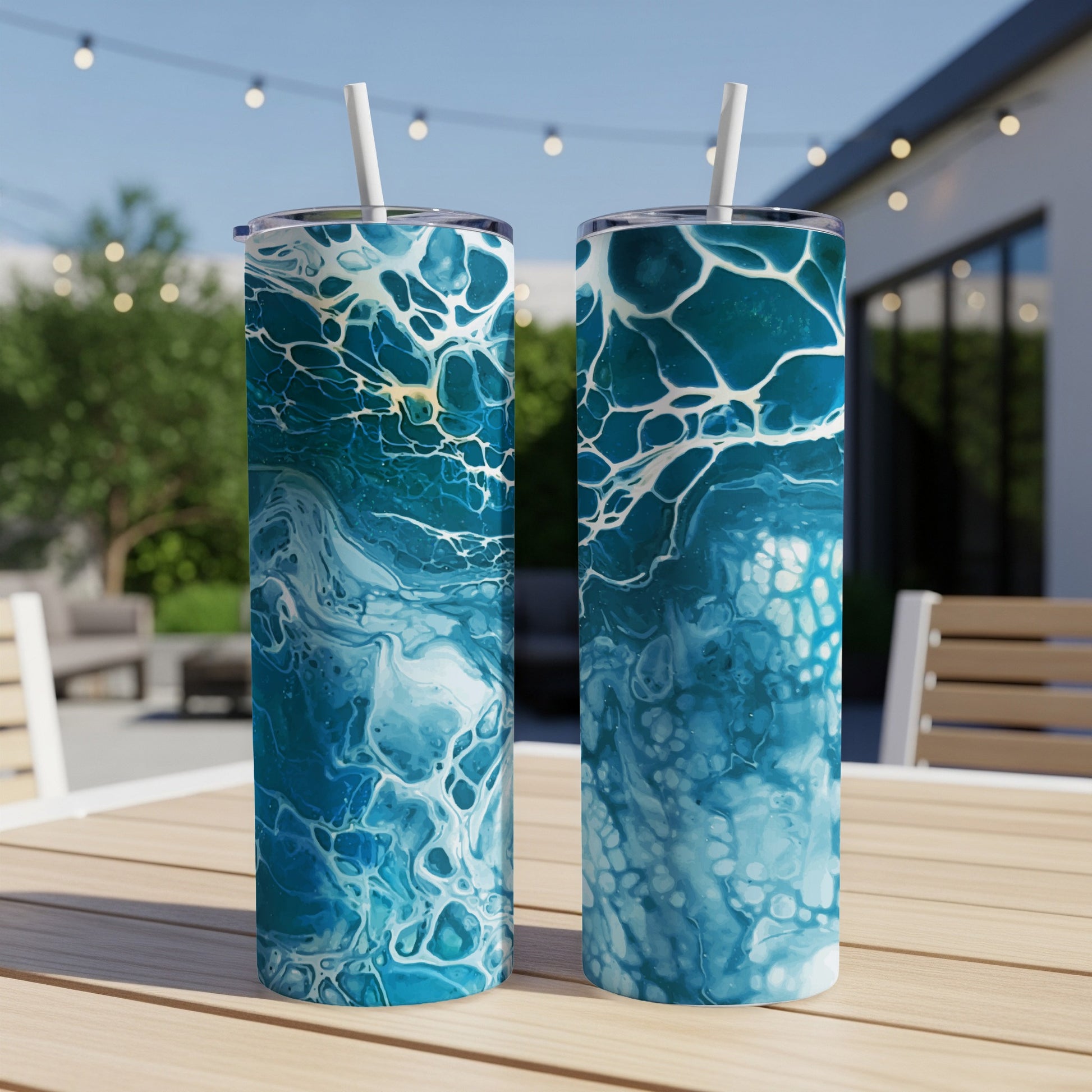 Two tumblers with a blue and white fluid art pattern, on a table outdoors.