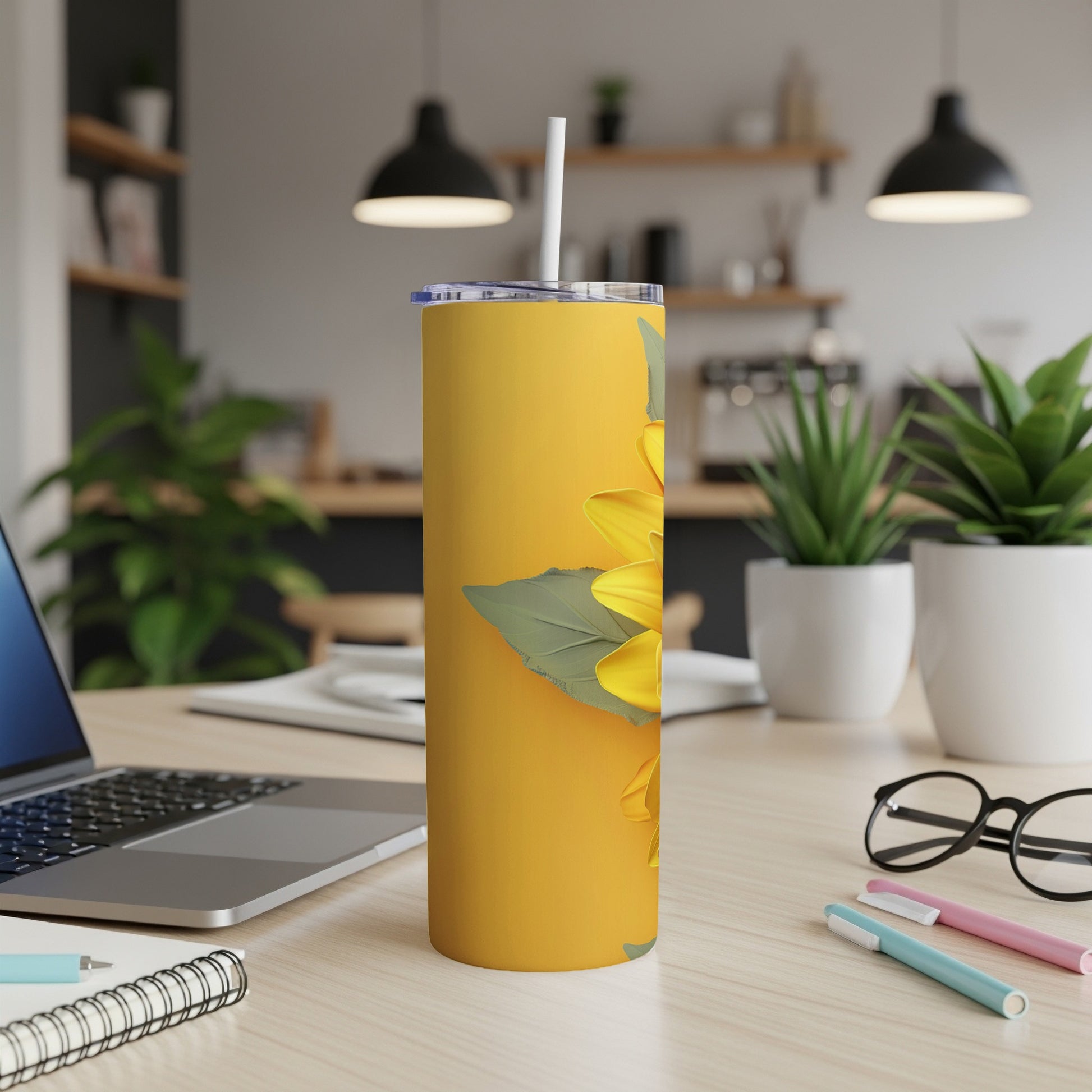 Yellow tumbler with a large sunflower design and white straw on a desk.
