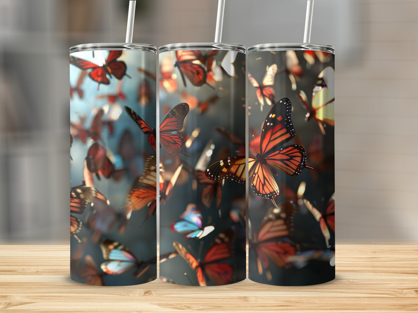 Three tumblers with a monarch butterfly design against a blurred background.