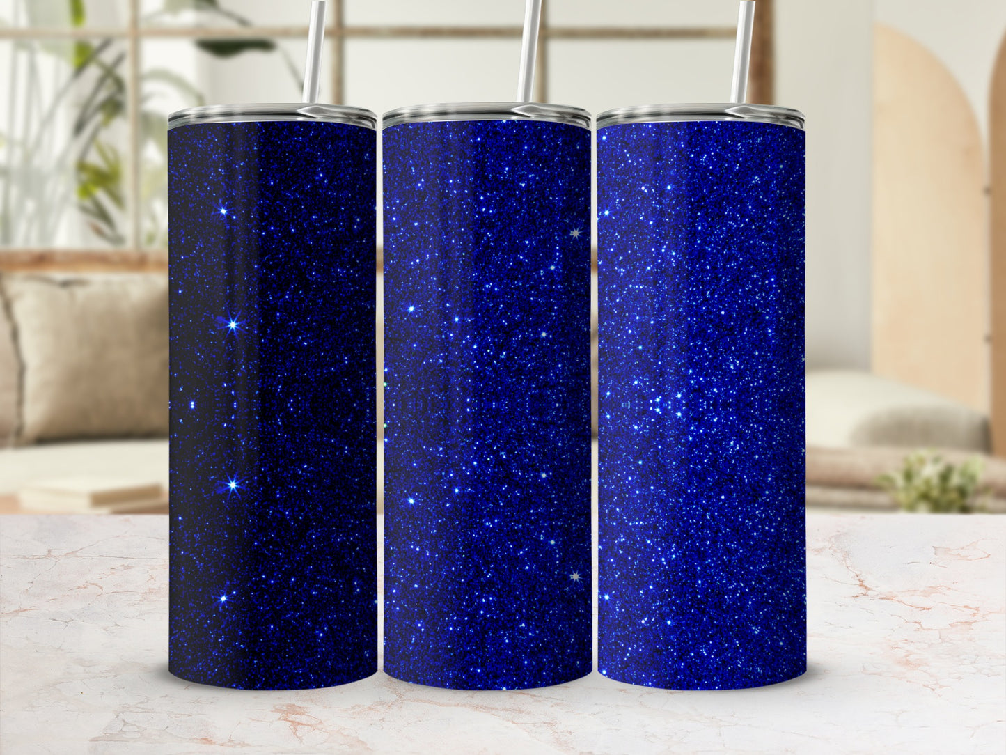 Three blue glitter tumblers with straws on a marble surface.