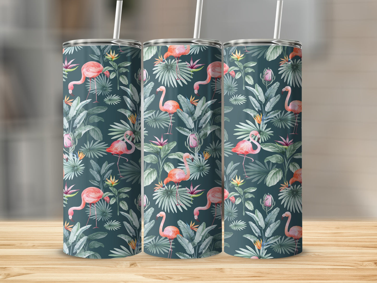 Three tumblers with a flamingo and tropical leaf pattern on a wooden surface.
