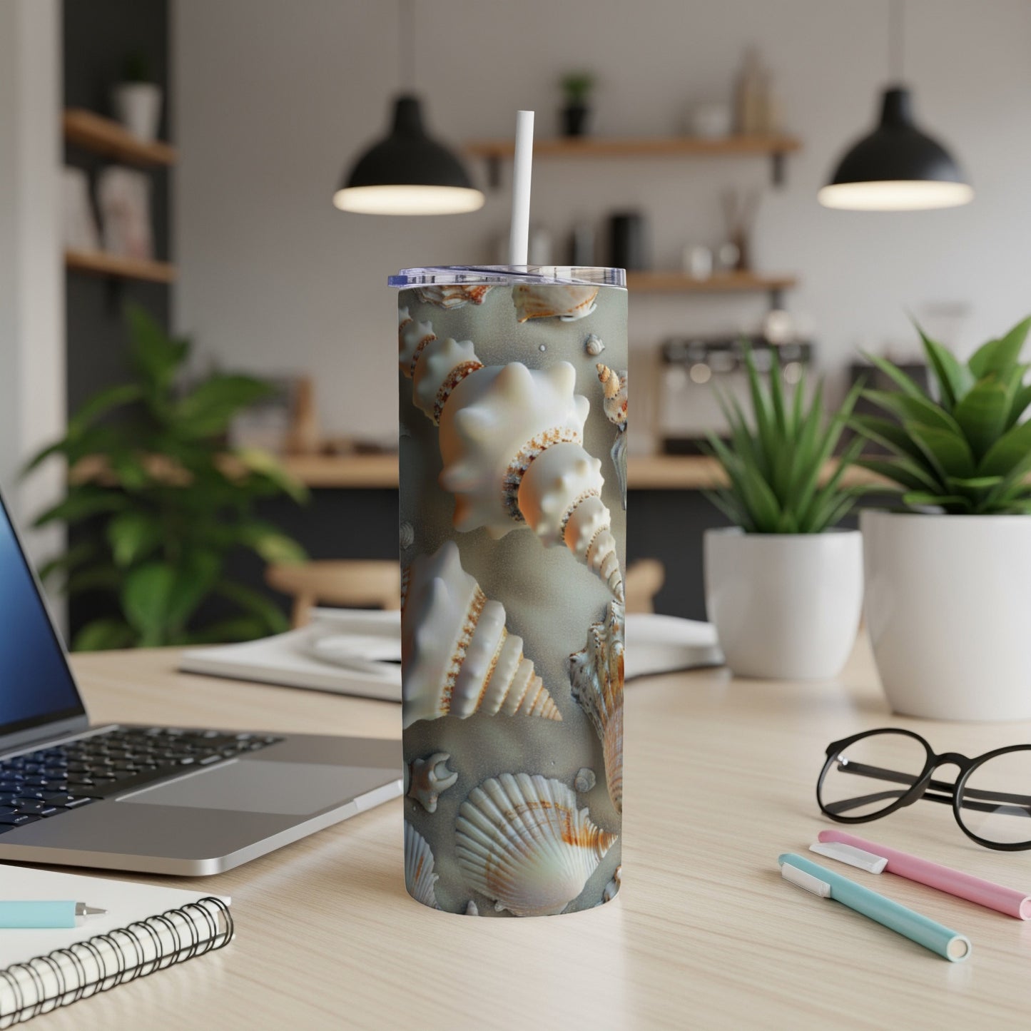 Tumbler with seashell pattern and beach sand background.