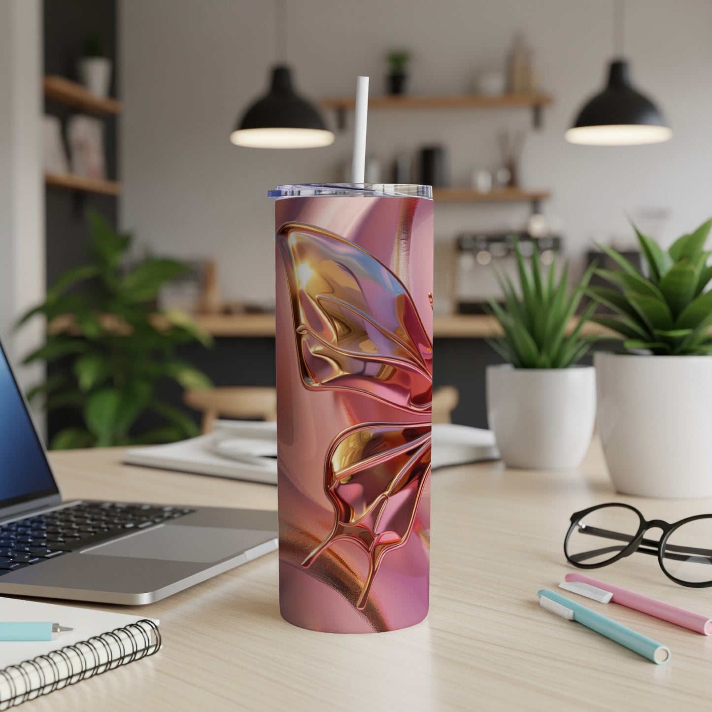 Pink and gold butterfly tumbler with straw on desk.