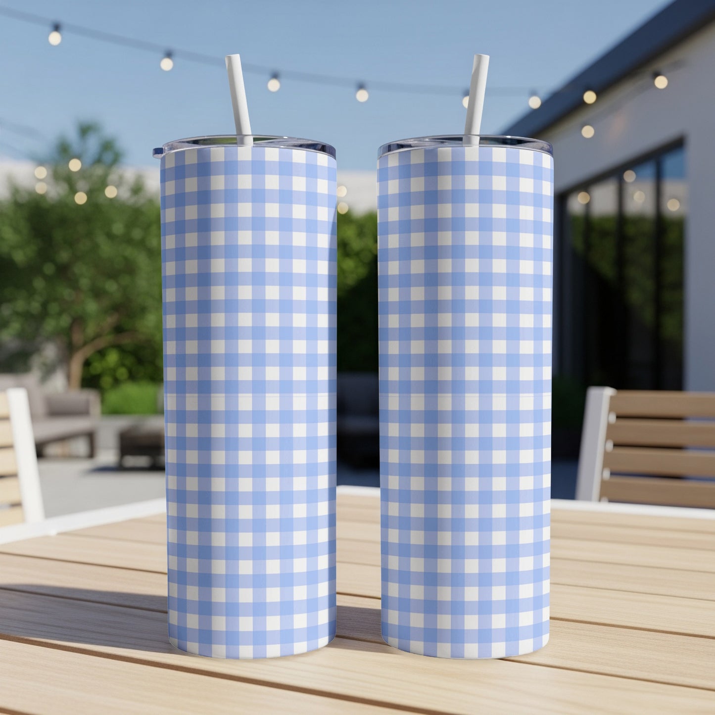 Two blue and white checkered tumblers with straws on a wooden table.