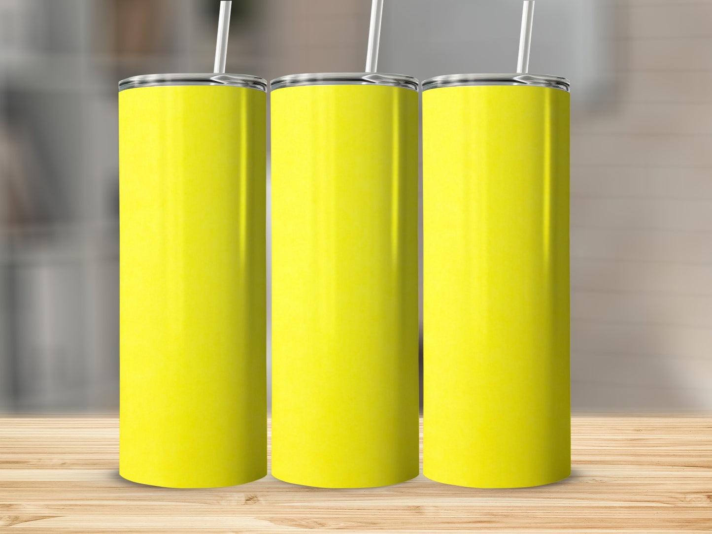 Three blank yellow tumblers with straws on a wooden surface.